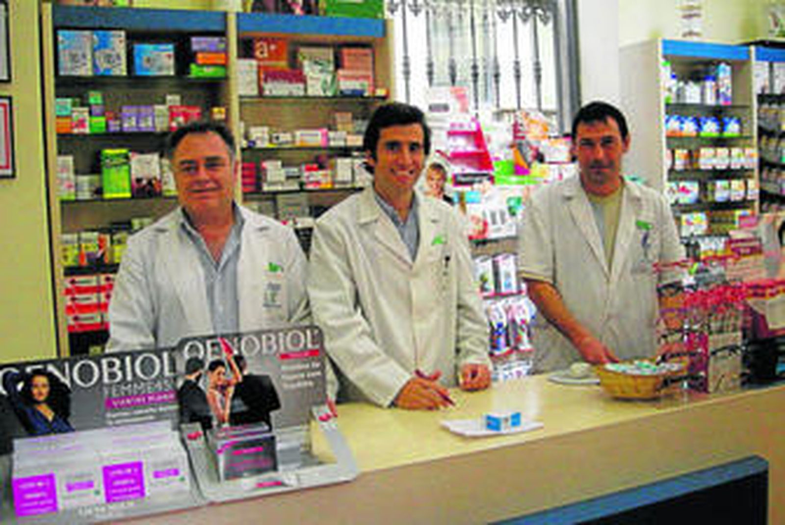 Miguel Gallego, en el centro, junto a Paco y Antonio en el mostrador de la farmacia.