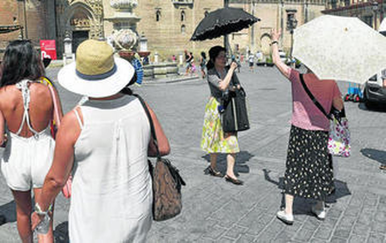 Turistas protegiéndose del sol en el entorno de la Catedral.