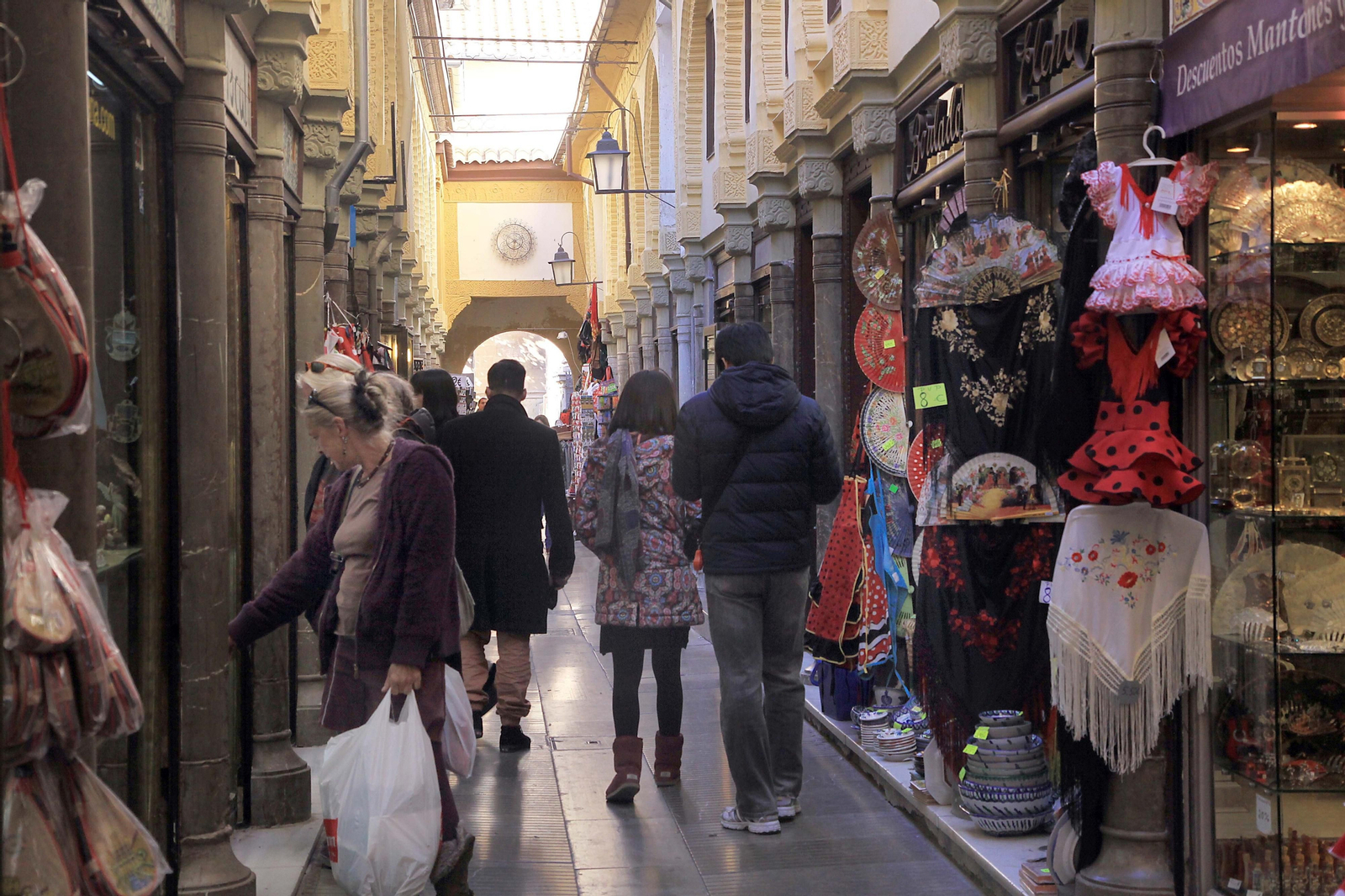 Varias personas pasean por los comercios de Alcaicería