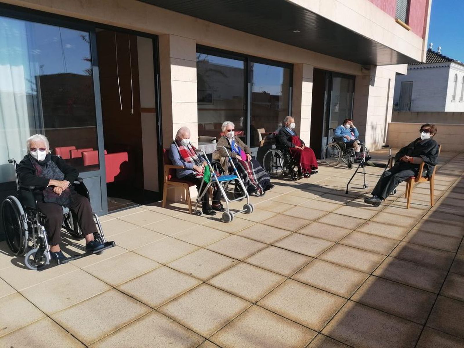 Varios mayores residentes del asilo Ignacio Gómez Millán, en Palomares del Río, disfrutan del sol en una de las zonas exteriores del centro.
