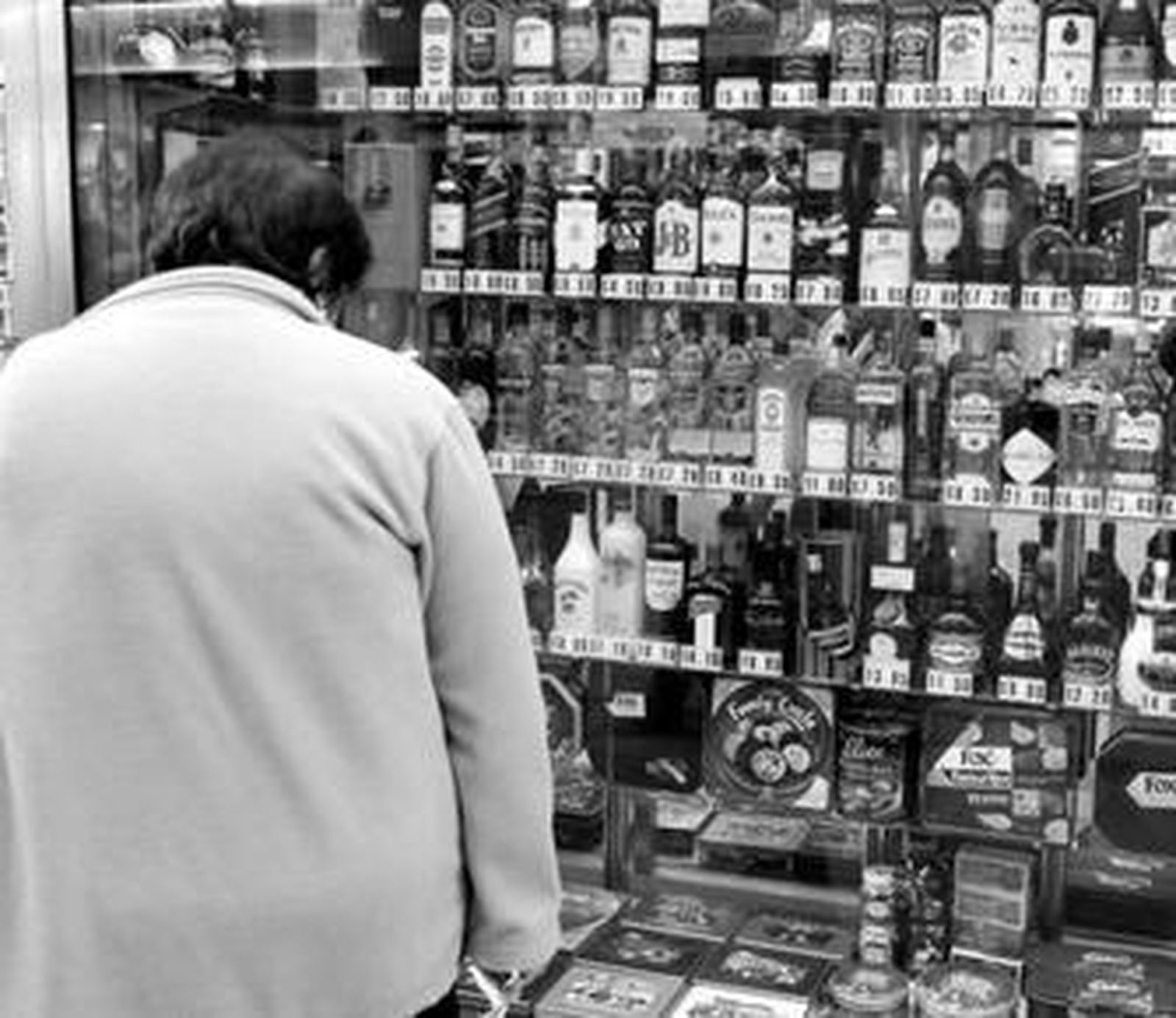 Una mujer mira los precios de bebidas alcohólicas en un escaparate del Peñón.