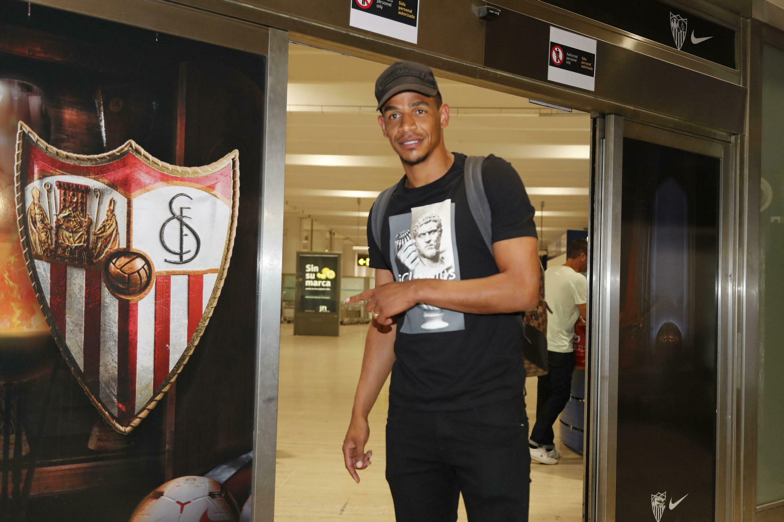 Fernando señala el escudo del Sevilla tras aterrizar a primera hora de la madrugada de hoy.