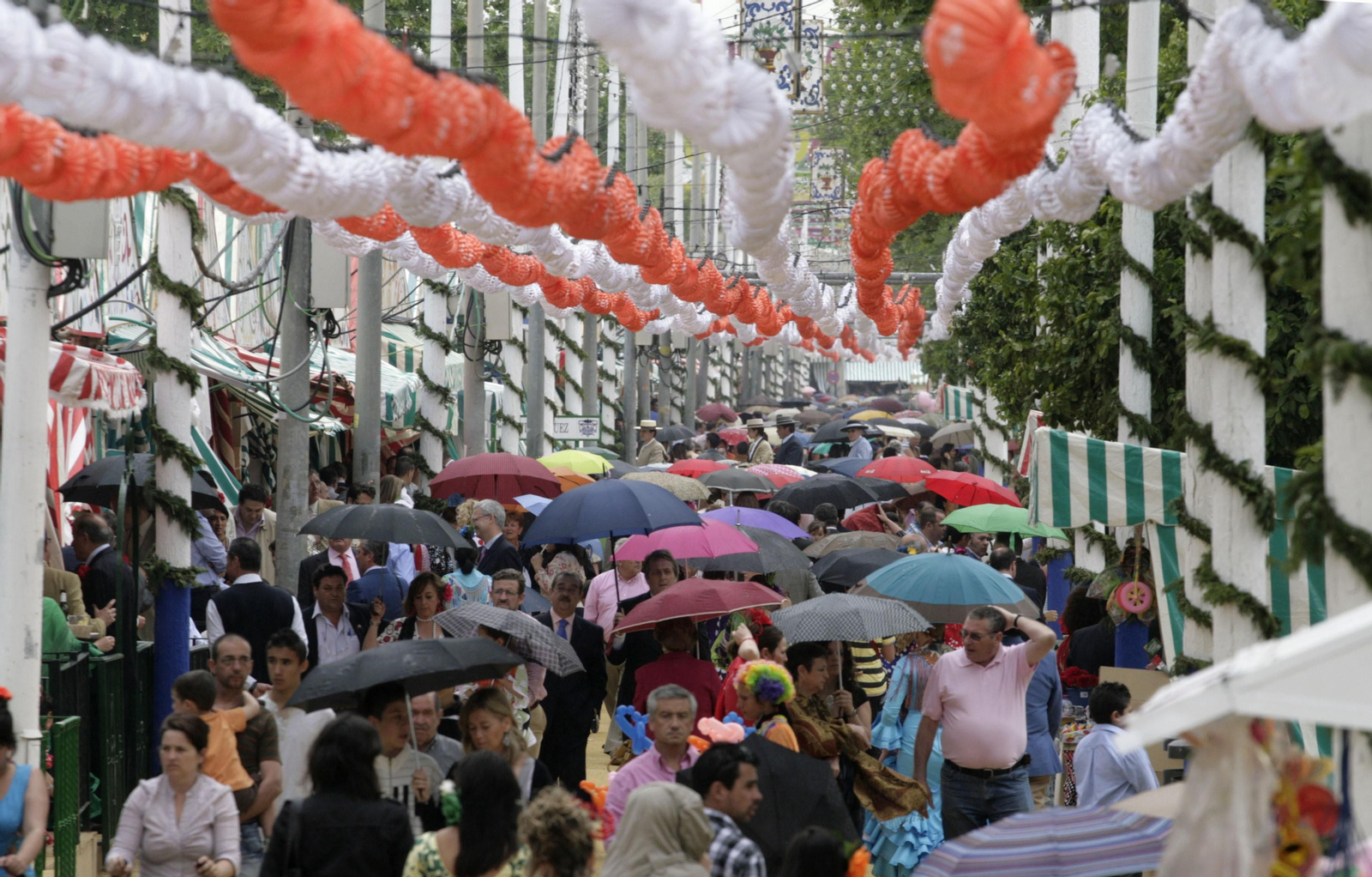 Gente con paraguas en el real de la Feria.