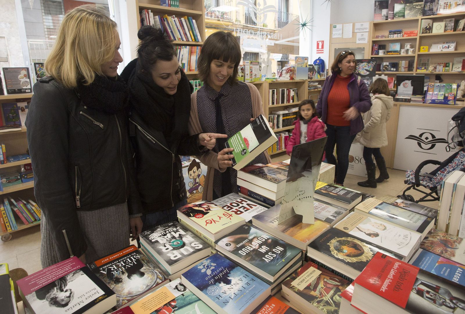 Varias mujeres ojean un ejemplar de un libro en una librería de la capital.