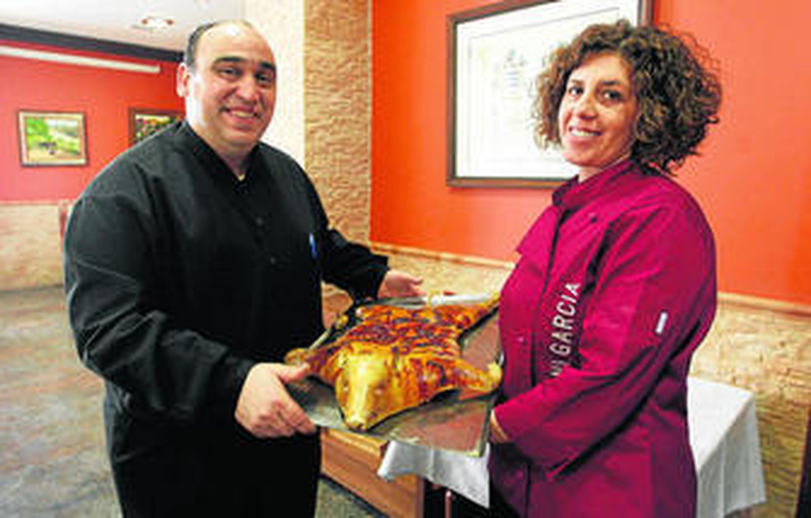 Curro Marín y Nani García presentan uno de los cochinillos asados que se desgustaron en la presentación de ayer.