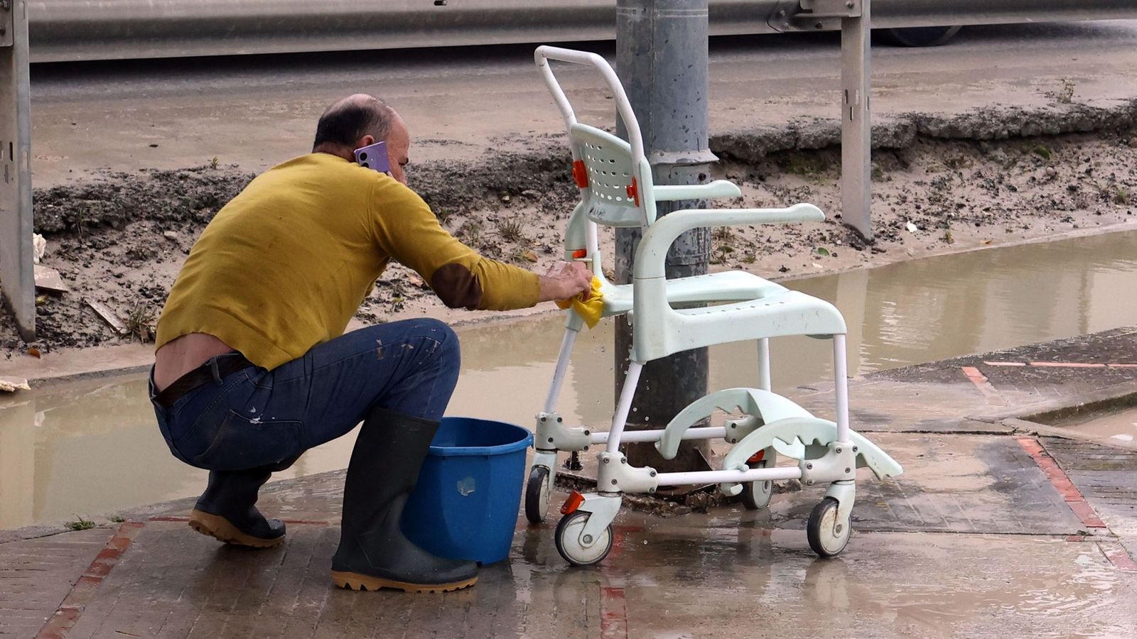 Antonio, vecino de El Portal, limpia una silla de ruedas frente a la vivienda de sus padres.