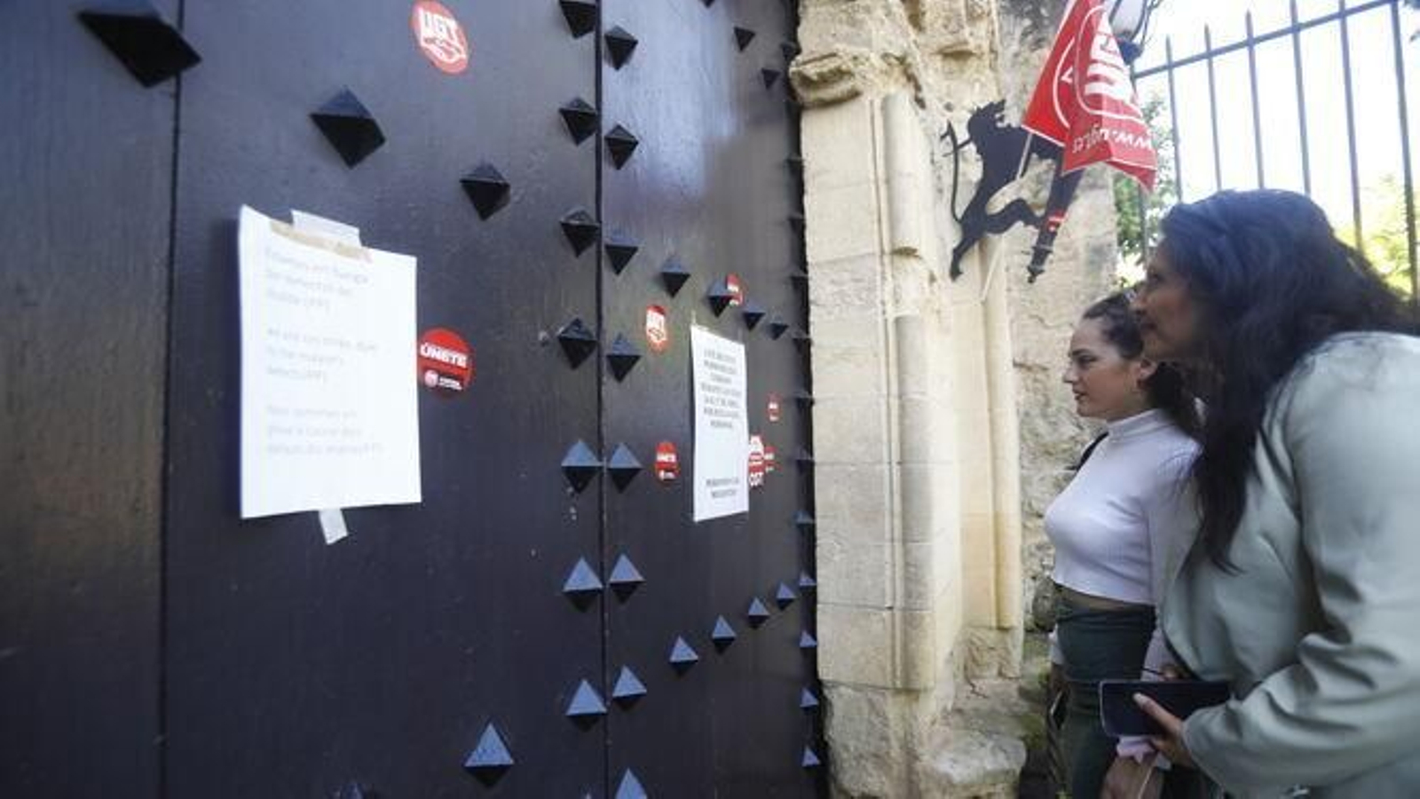 Dos personas leen los carteles pegados en la puerta del Alcázar el Jueves Santo del año pasado.