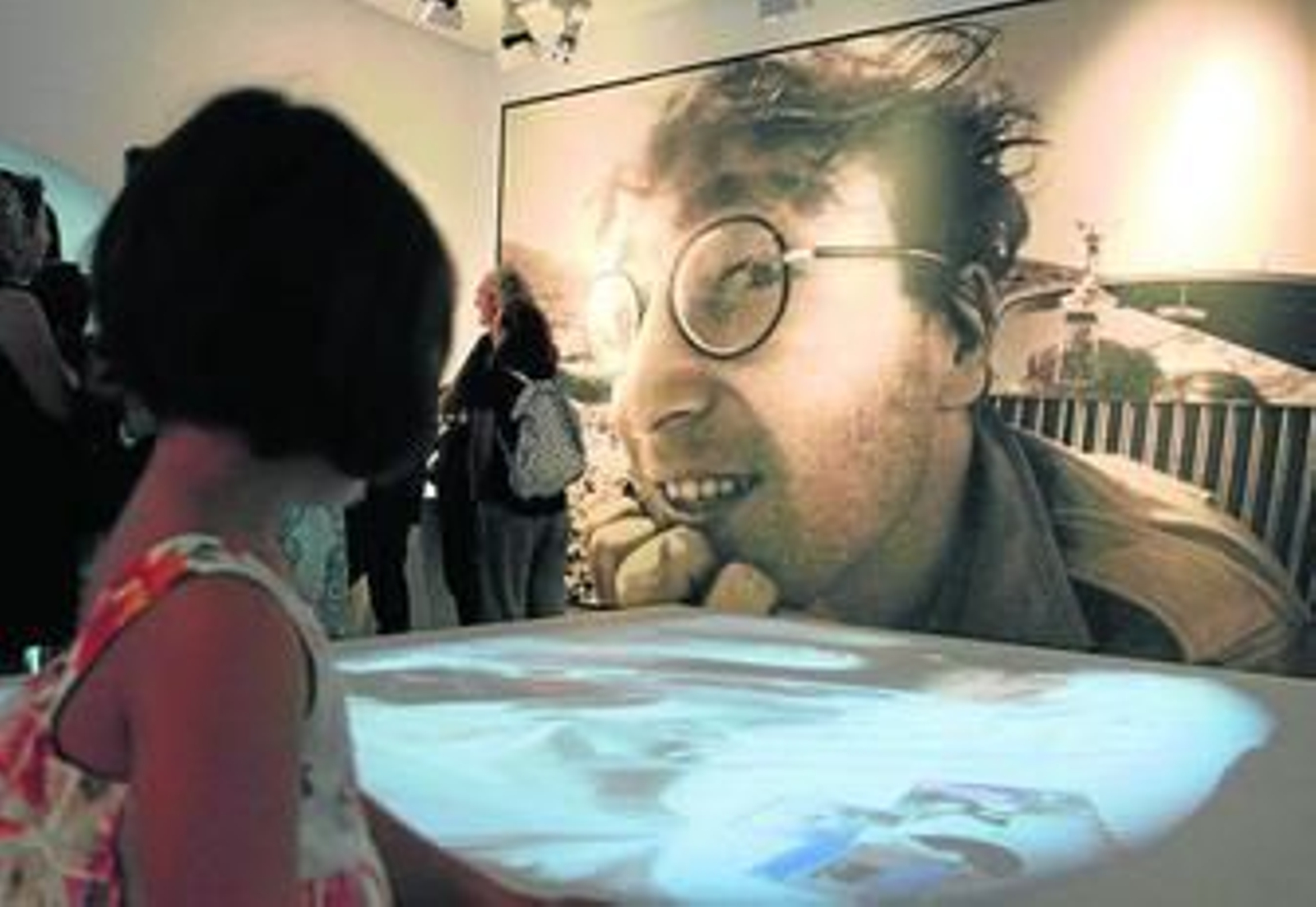 Una niña contempla la imagen de John Lennon en la Casa del Cine de Almería.