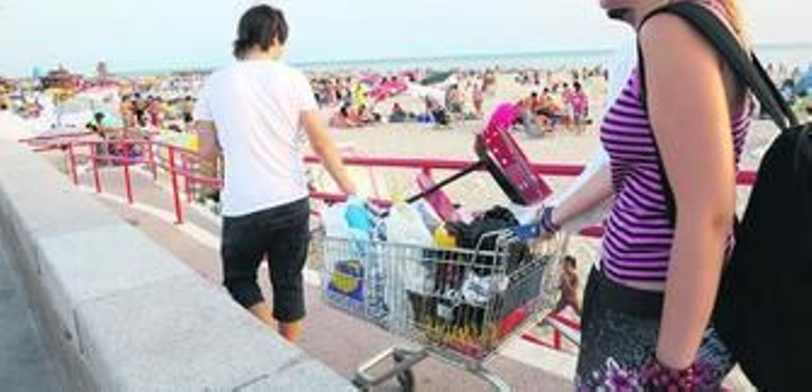 Un grupo de jóvenes llegando a la playa en la tarde de ayer con un carro cargado con una barbacoa y numerosas provisiones.