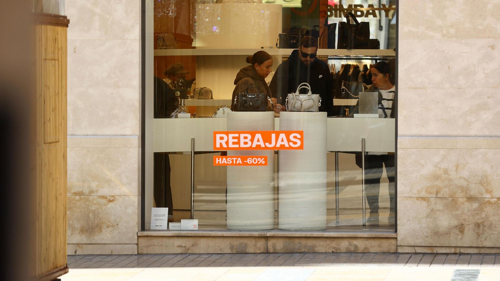 Una pareja observa un artículo en el interior de una tienda con descuentos.