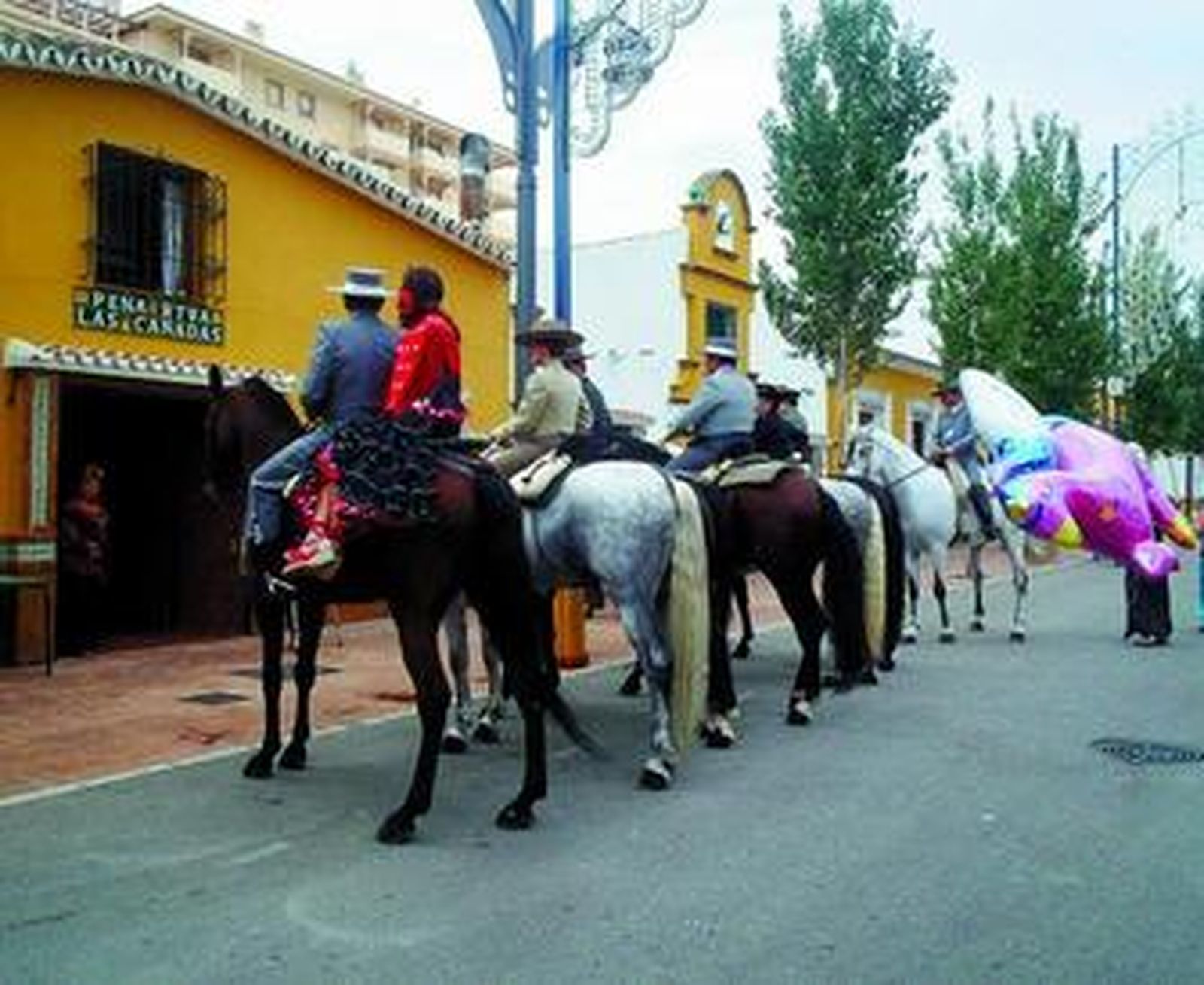Un grupo de caballistas descansan en una calle del recinto ferial.
