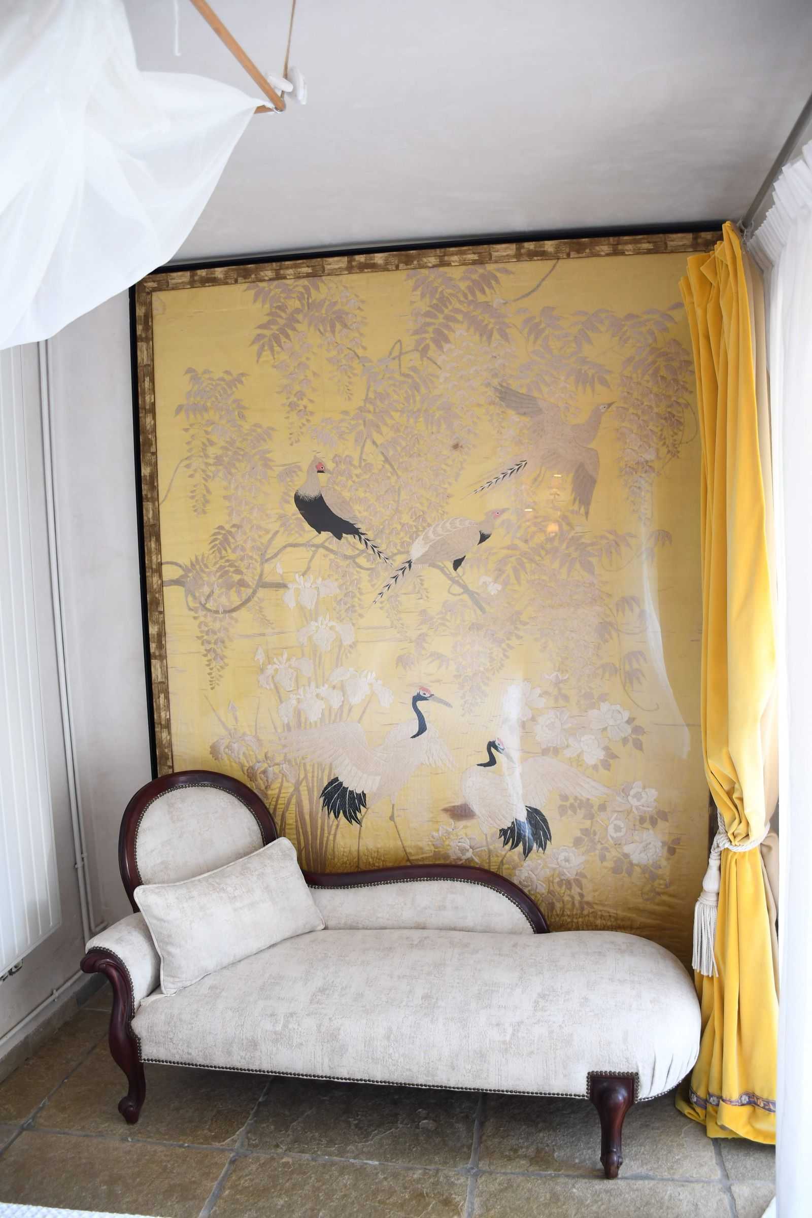 Longue de caoba tapizado en terciopelo de seda y, colgando, una antigua colcha de seda bordadas.