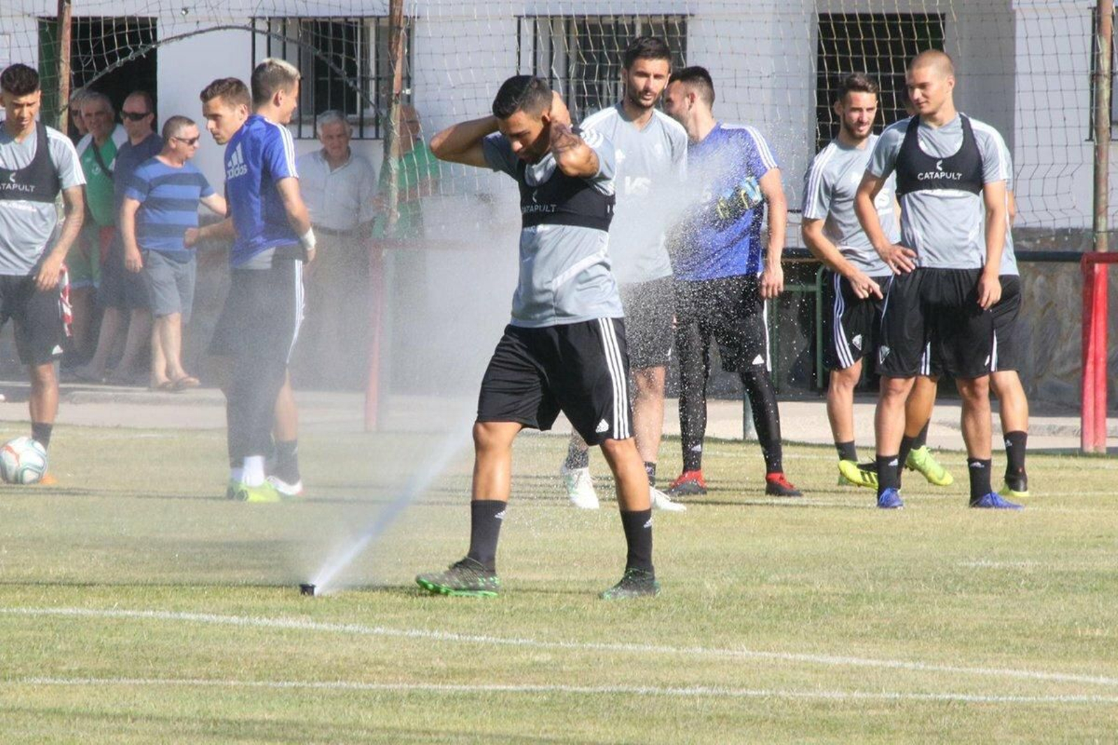 Dani Romera aprovecha un aspersor para refrescarse antes del entrenamiento.