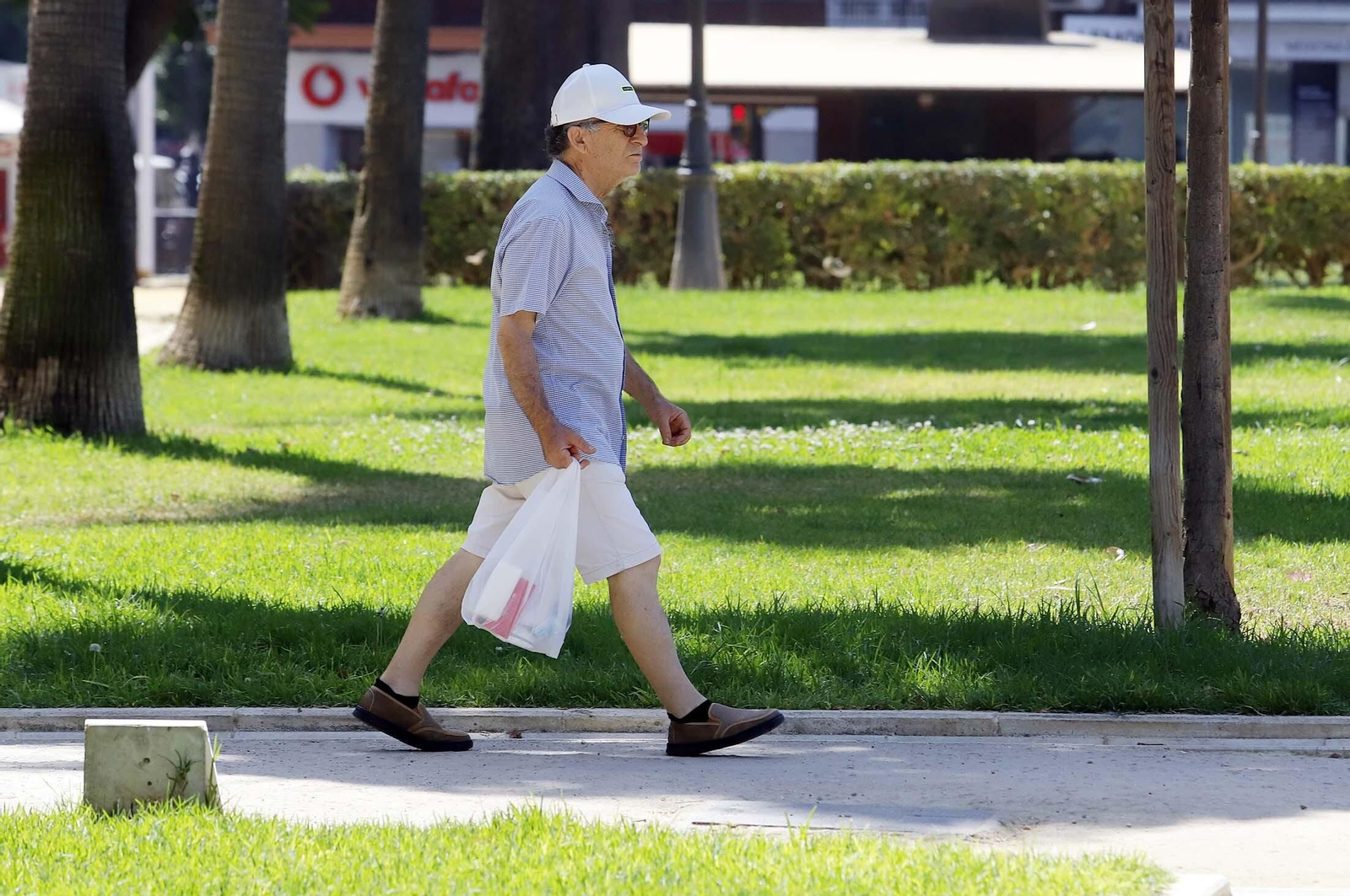 Un hombre pasea con su gorra para protegerse del sol.