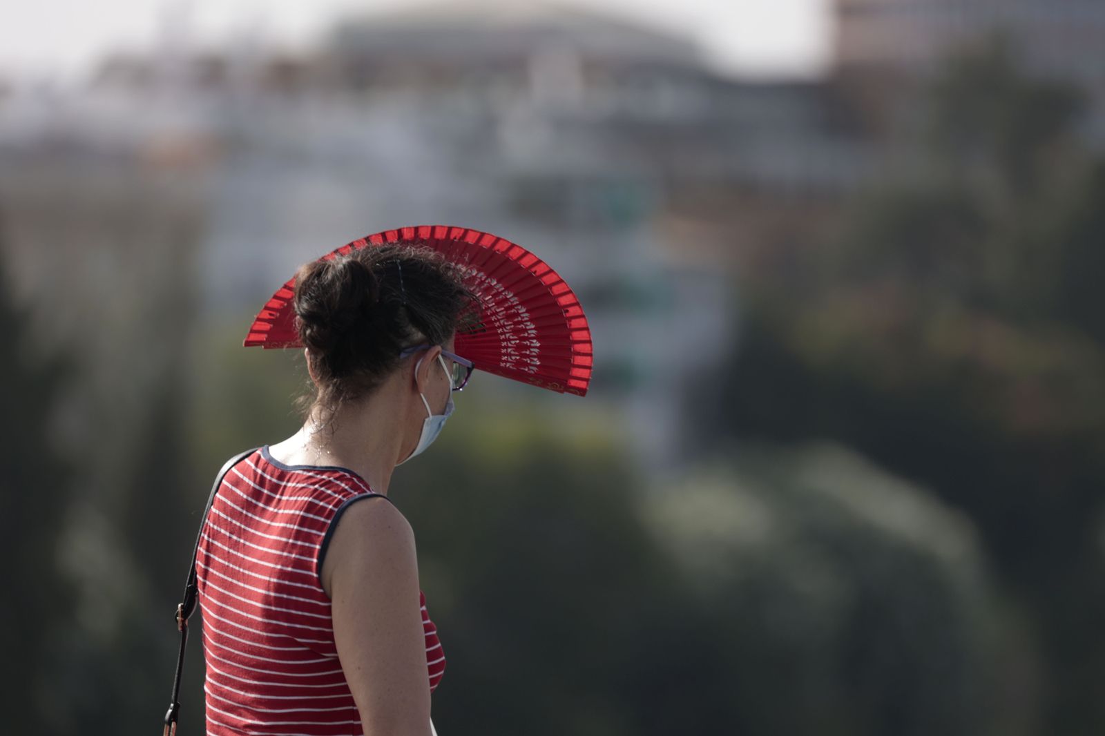 Una mujer se cubre el rostro del sol con un abanico.