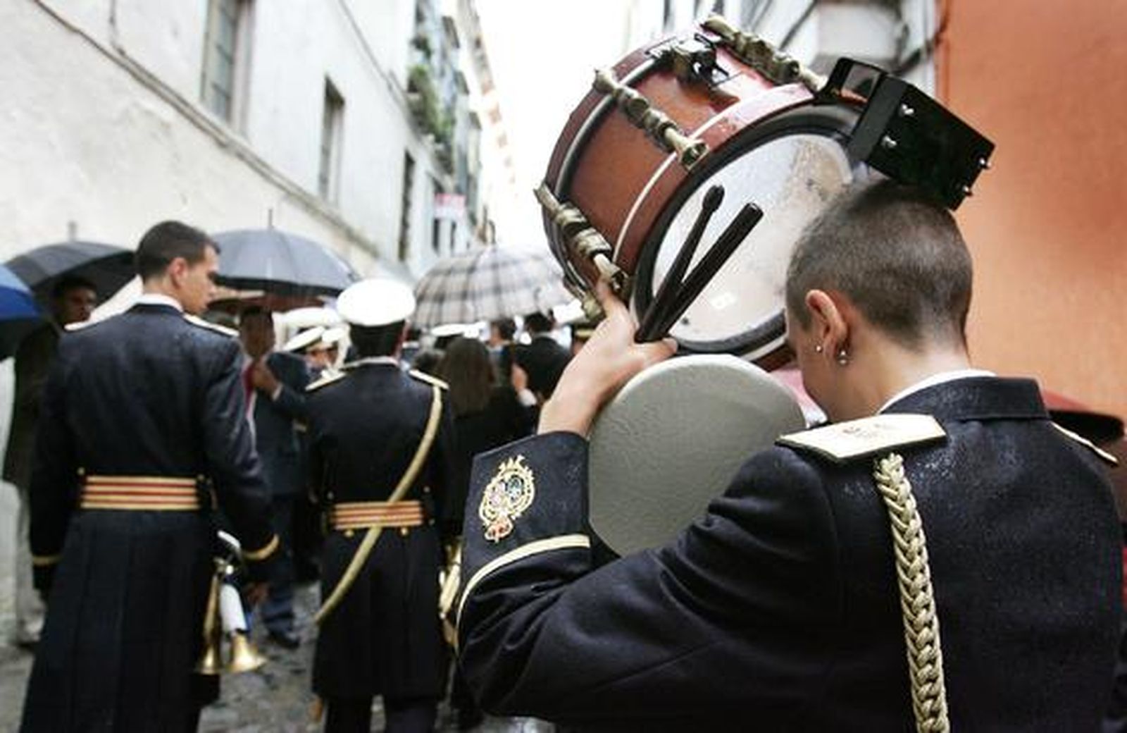 Un joven músico utiliza su tambor para protegerse de la lluvia.

Foto: Pascual