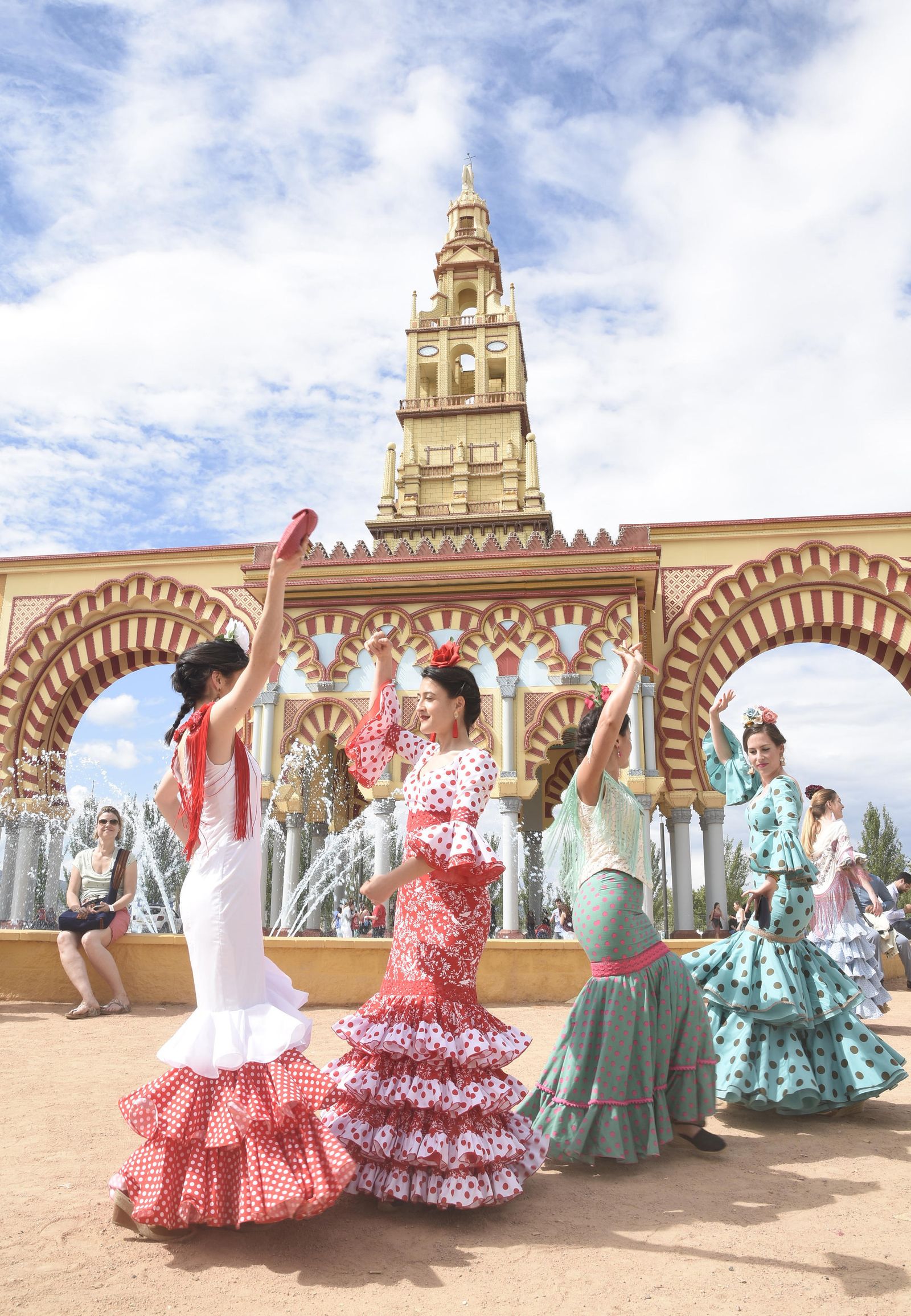Unas jóvenes bailan sevillanas en la entrada de El Arenal.