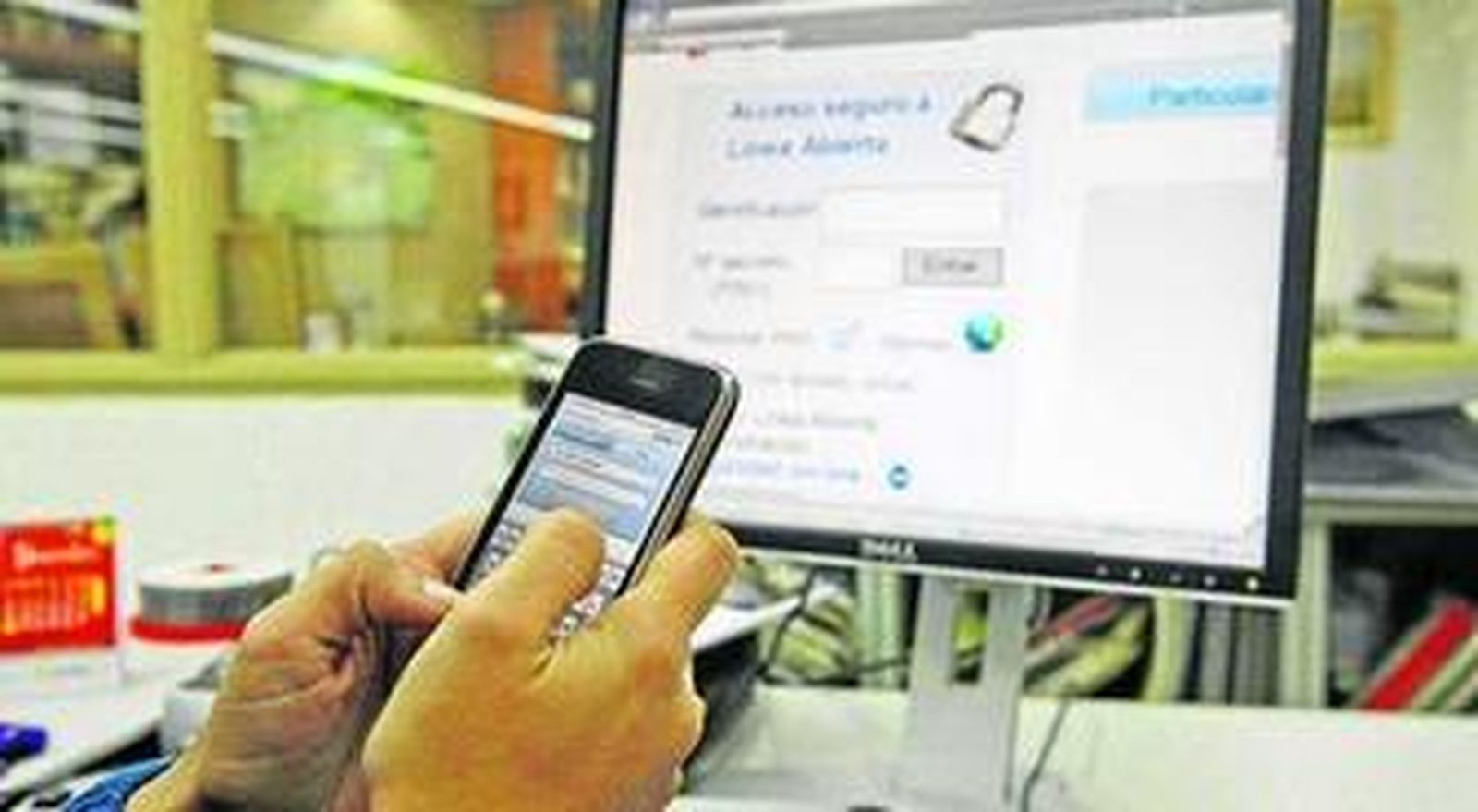 Un usuario consulta su 'smartphone' delante de un ordenador.