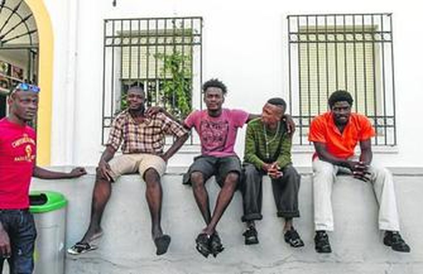 1. Un grupo de inmigrantes sentado a la entrada del centro Tartessos, situado en la esquina de Juan Carlos I con Trille. 2. Moussa, de Burkina Faso, tras la puerta de acceso al edificio. Este joven llegó a Cádiz el 4 de julio procedente del CIE de Tarifa. 3. Varios de los inmigrantes en la sala de informática, el lugar más solicitado, ya que es donde pueden contactar con familiares y compatriotas a través de internet. 4. Boris Jodelle, camerunés de 19 años que llegó el pasado miércoles a Tartessos. Él durmió su primera noche en la litera que se instaló en el pasillo por falta de camas. 5. Un joven inmigrante en uno de los dormitorios del centro ordenando la habitación.