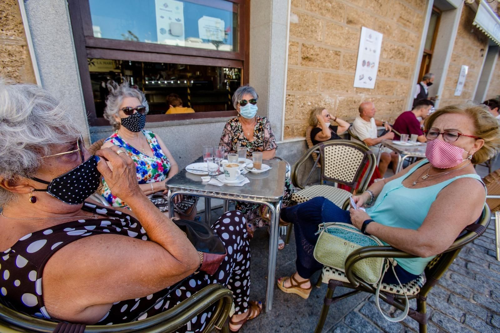 Un grupo de mujeres con mascarillas en una terraza.