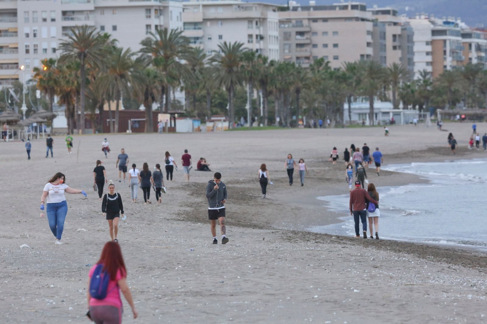 Varias personas pasean por la playa en Málaga capital.
