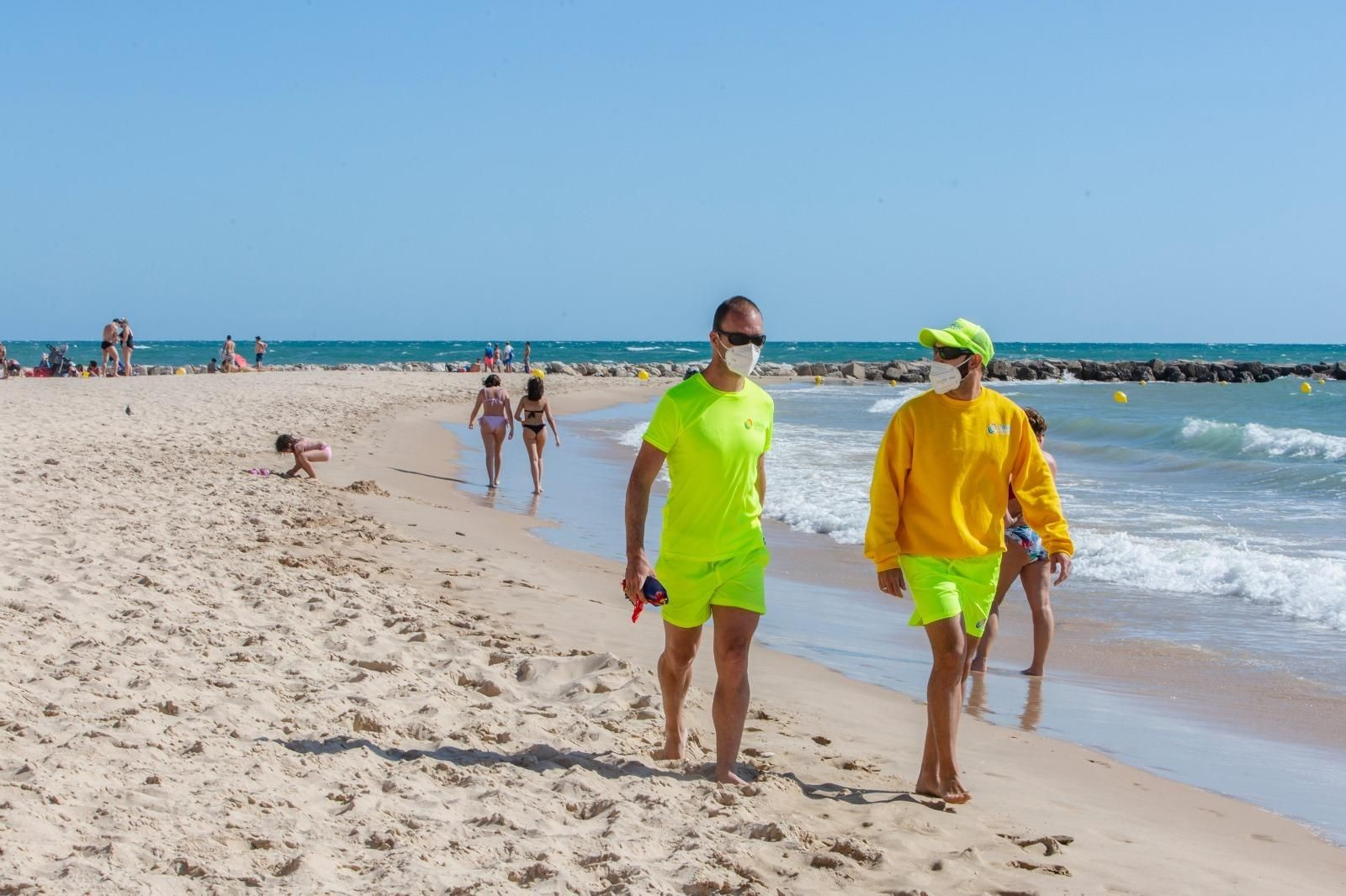 Dos socorristas con mascarillas, por una playa de la ciudad.
