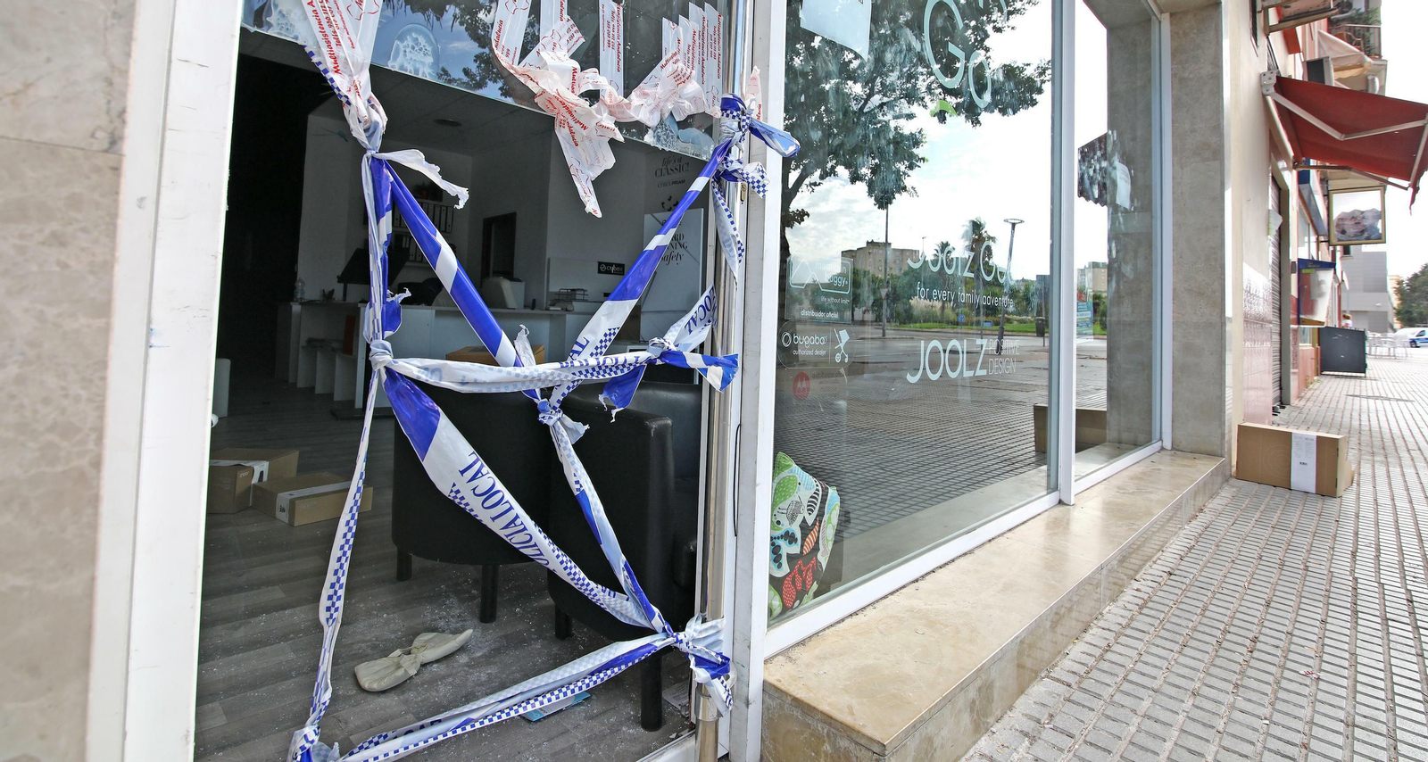 La policía precinta la puerta rota por la que accedieron las personas que perpetraron la tienda