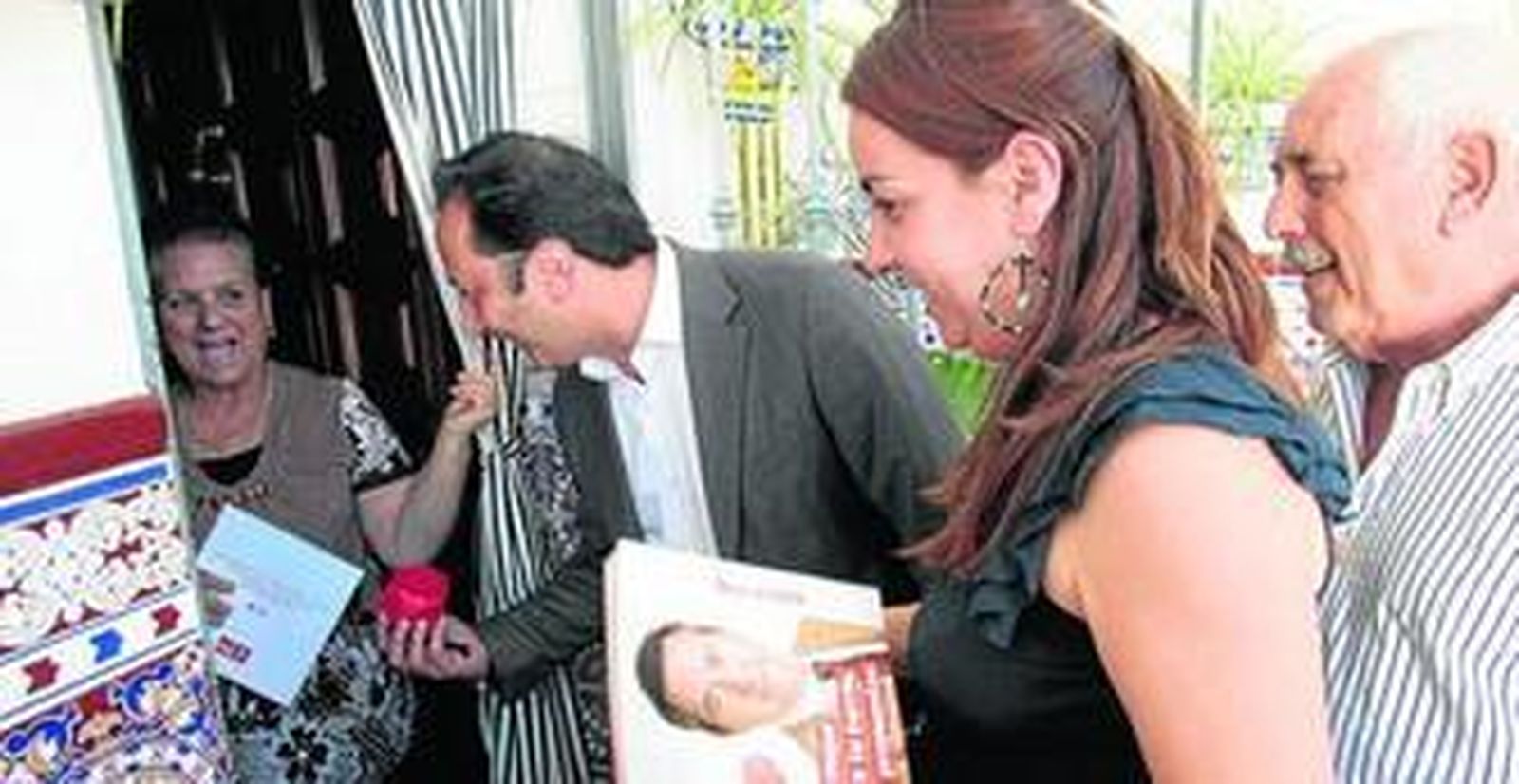 Celis da una bolsa del PSOE a Aurora, la nieta de una vecina de las colectivas, junto a Encarnación Martínez y Tomás Bancalero.