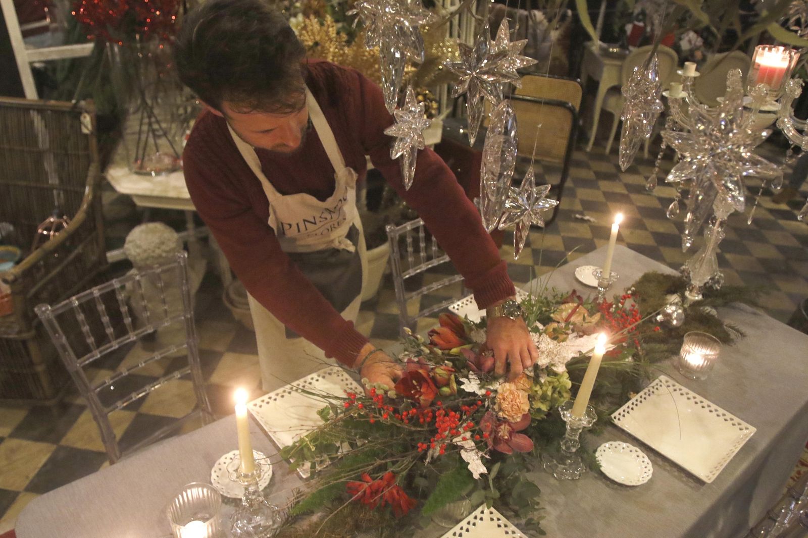 Luis Nevado coloca ornamentación floral sobre una mesa de comedor.