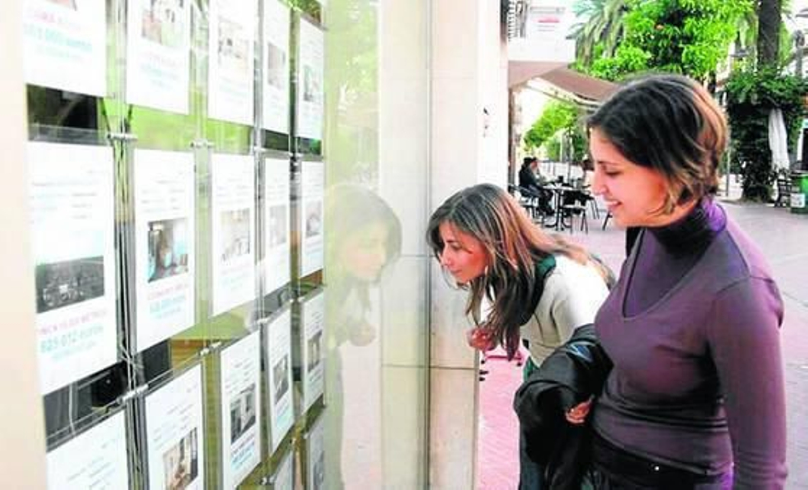 Unas chicas buscan piso en una inmobiliaria.
