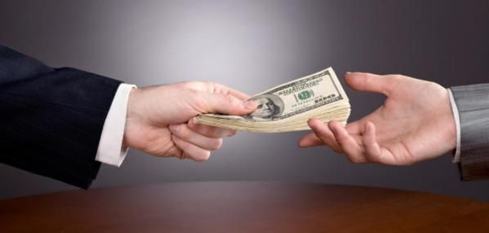 Dos manos intercambiándose dinero.