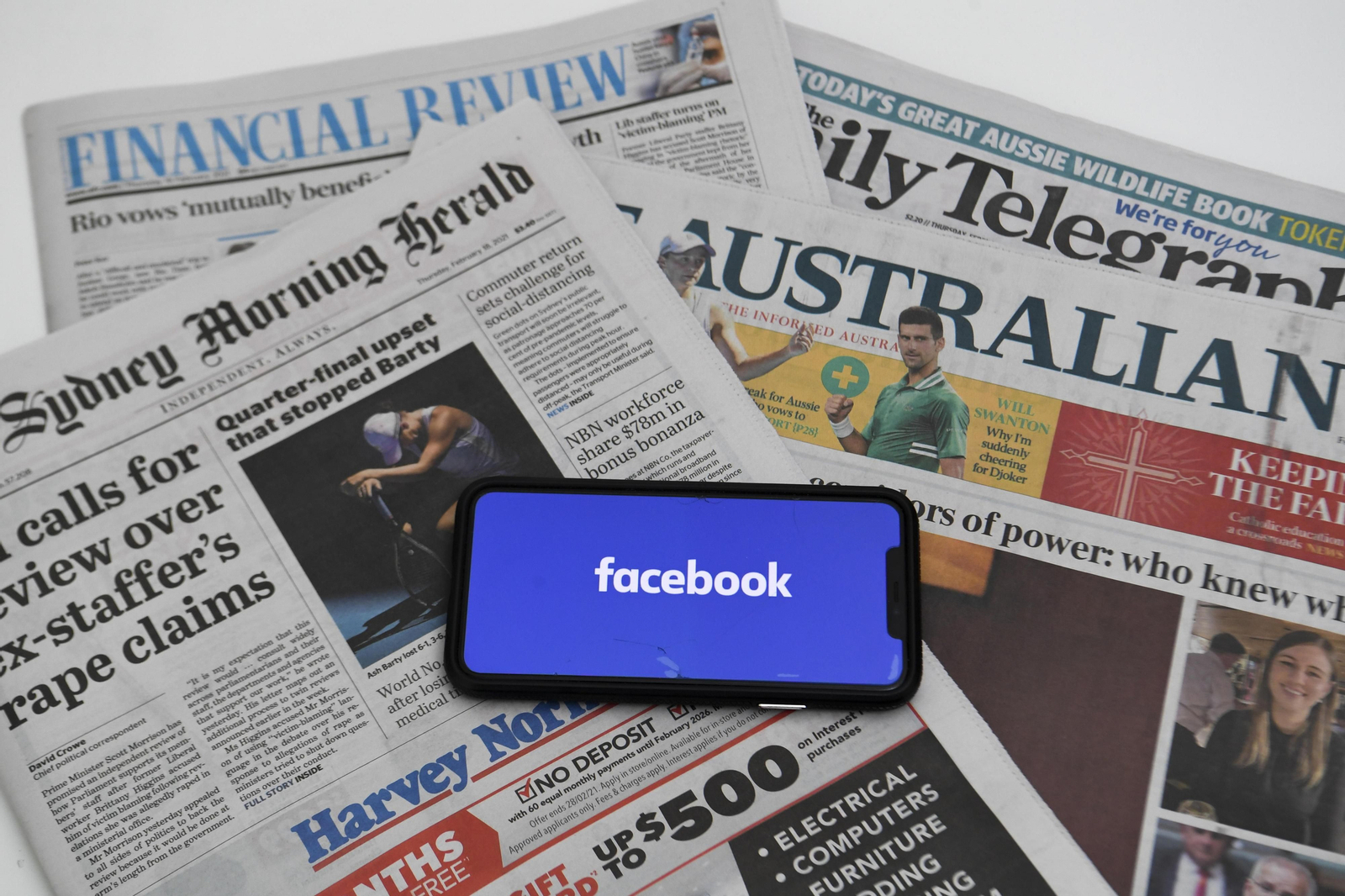 Un móvil con el logo de Facebook sobre varios periódicos australianos.