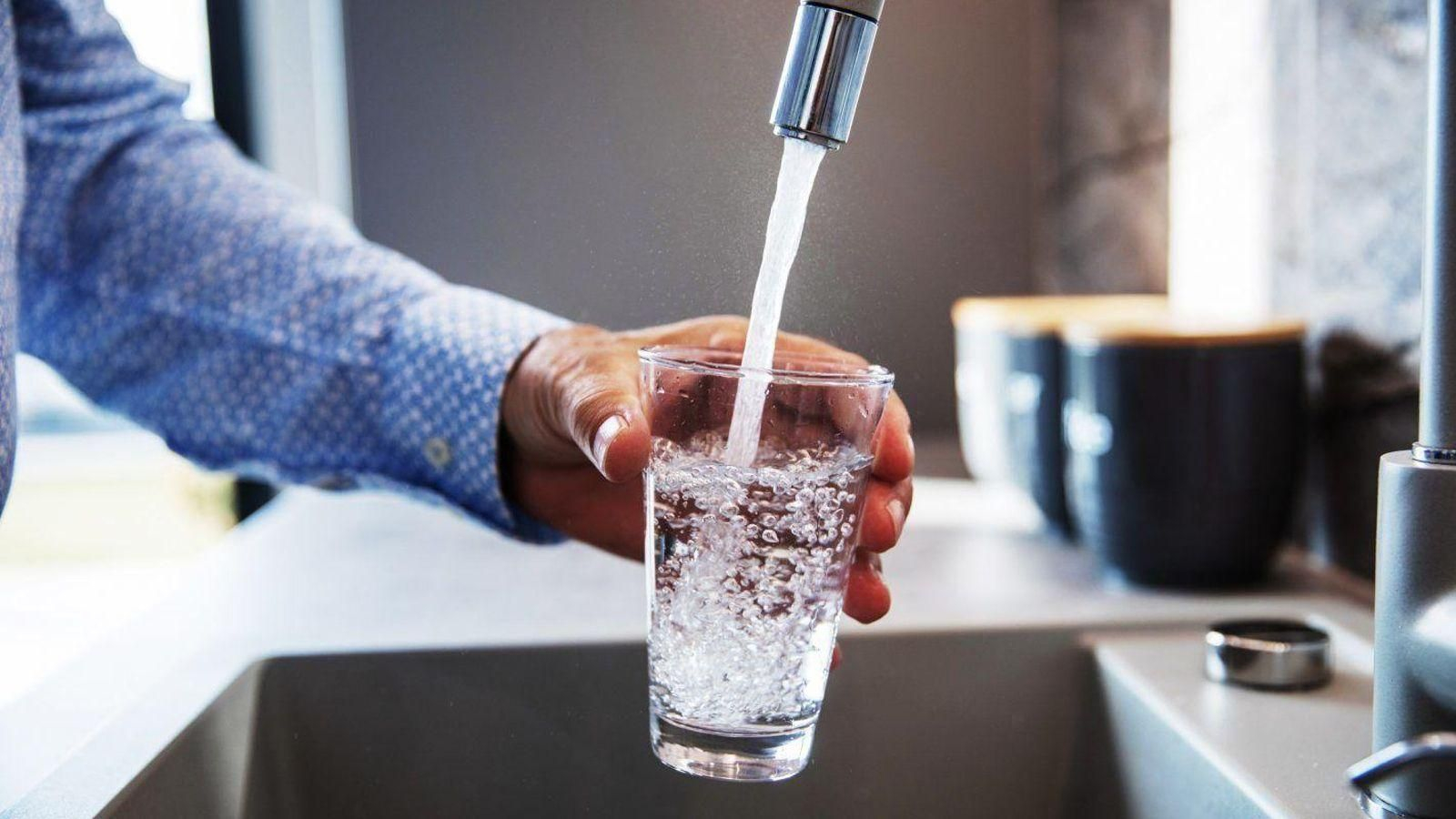 Un hombre coge agua de un grifo.