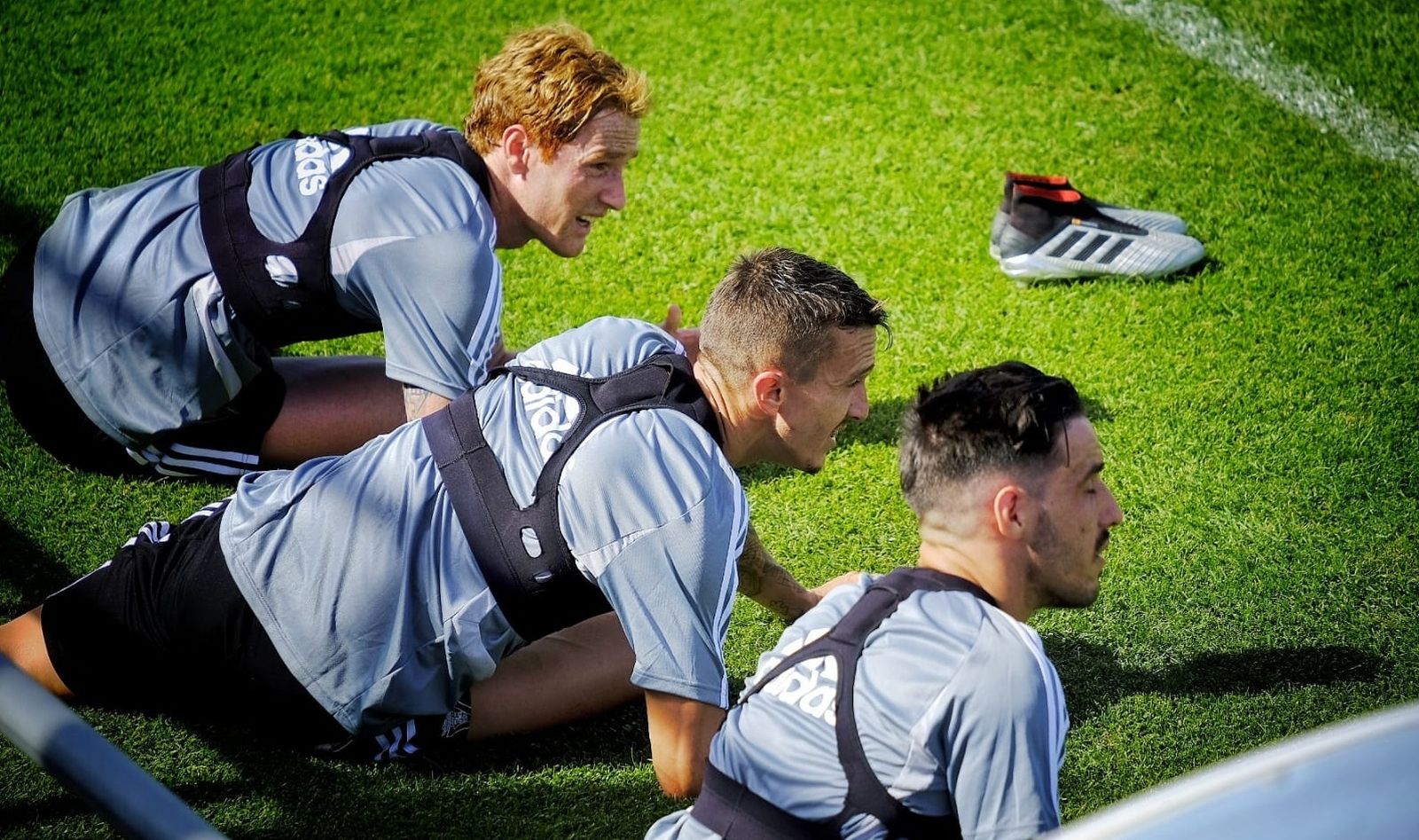 Álex Fernández, Salvi e Iza fijan sus miradas mientras estiran sobre el terreno de juego.