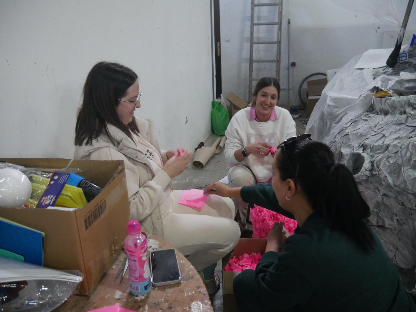 Un grupo de jóvenes canjilonas elaboran 'plumas' de papel para su carroza.