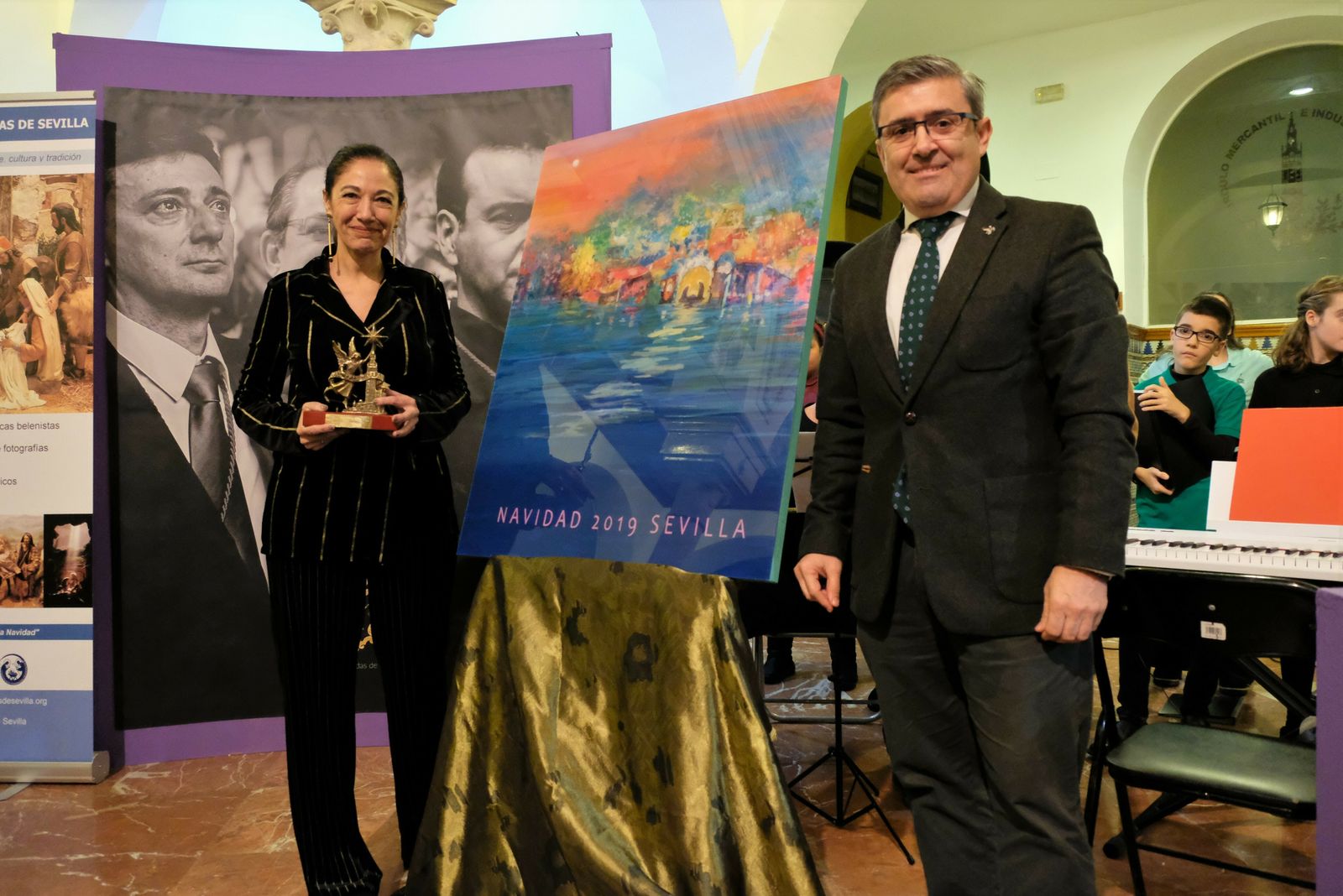 La autora del cartel y el presidente de la Asociación de Belenistas junto a la obra.