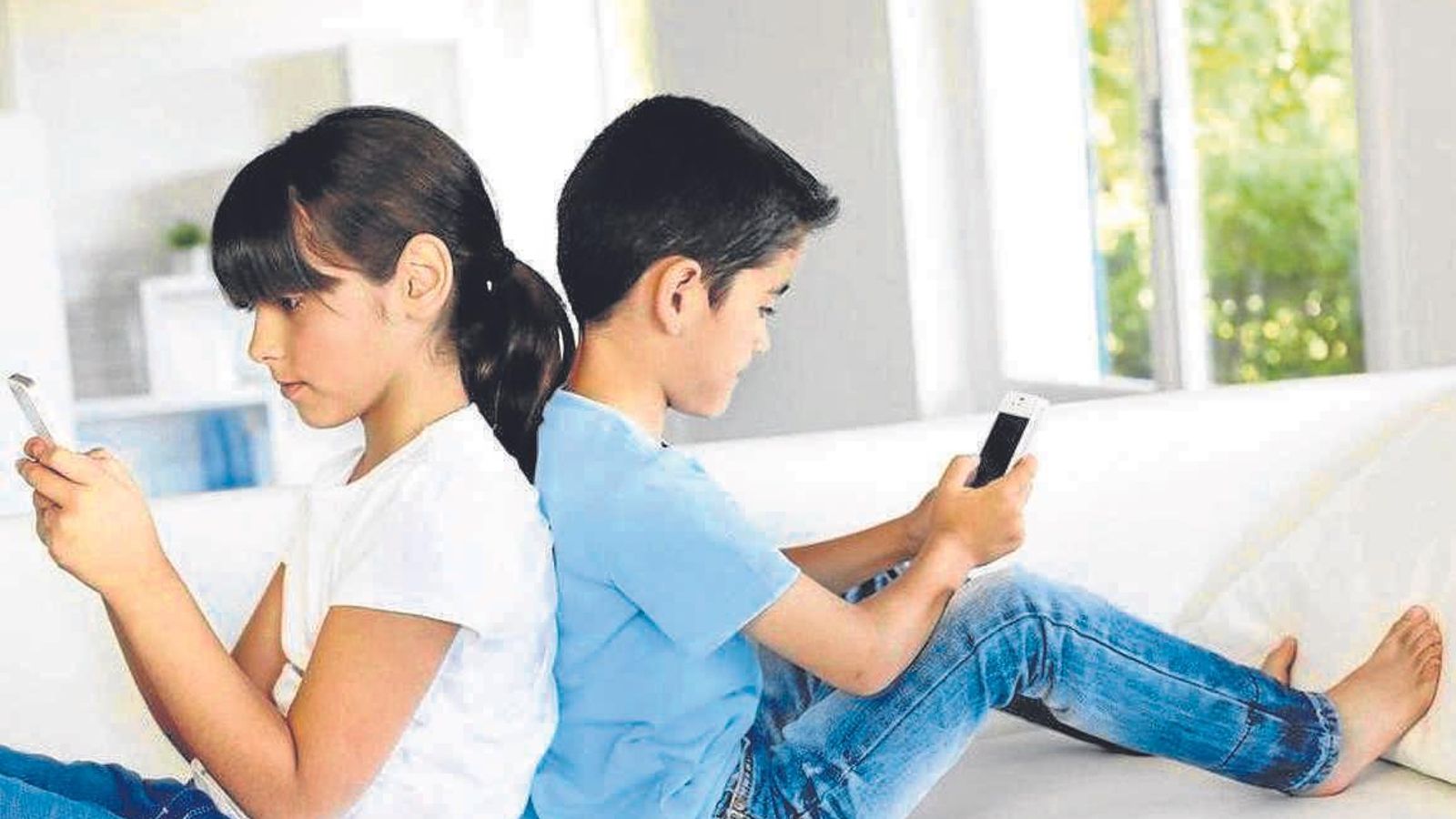 Dos menores juegan con sus teléfonos móviles.