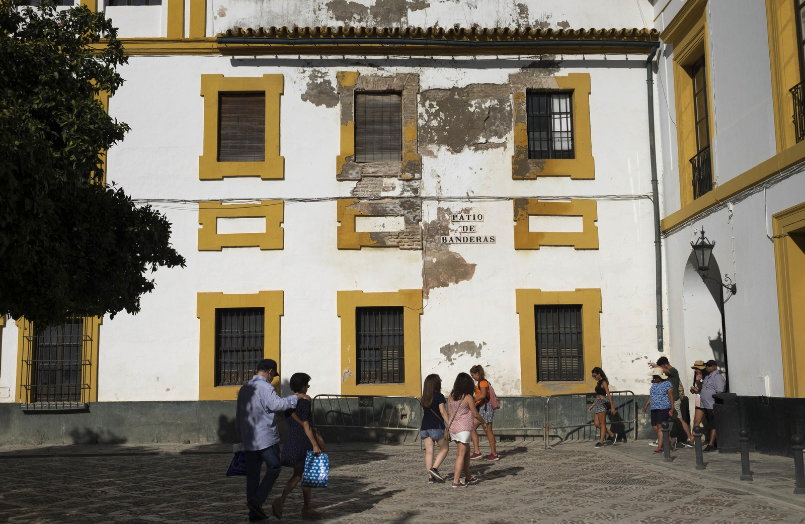 Varias personas caminan junto a la fachada de la casa que será restaurada, en el número 12 del Patio de Banderas.