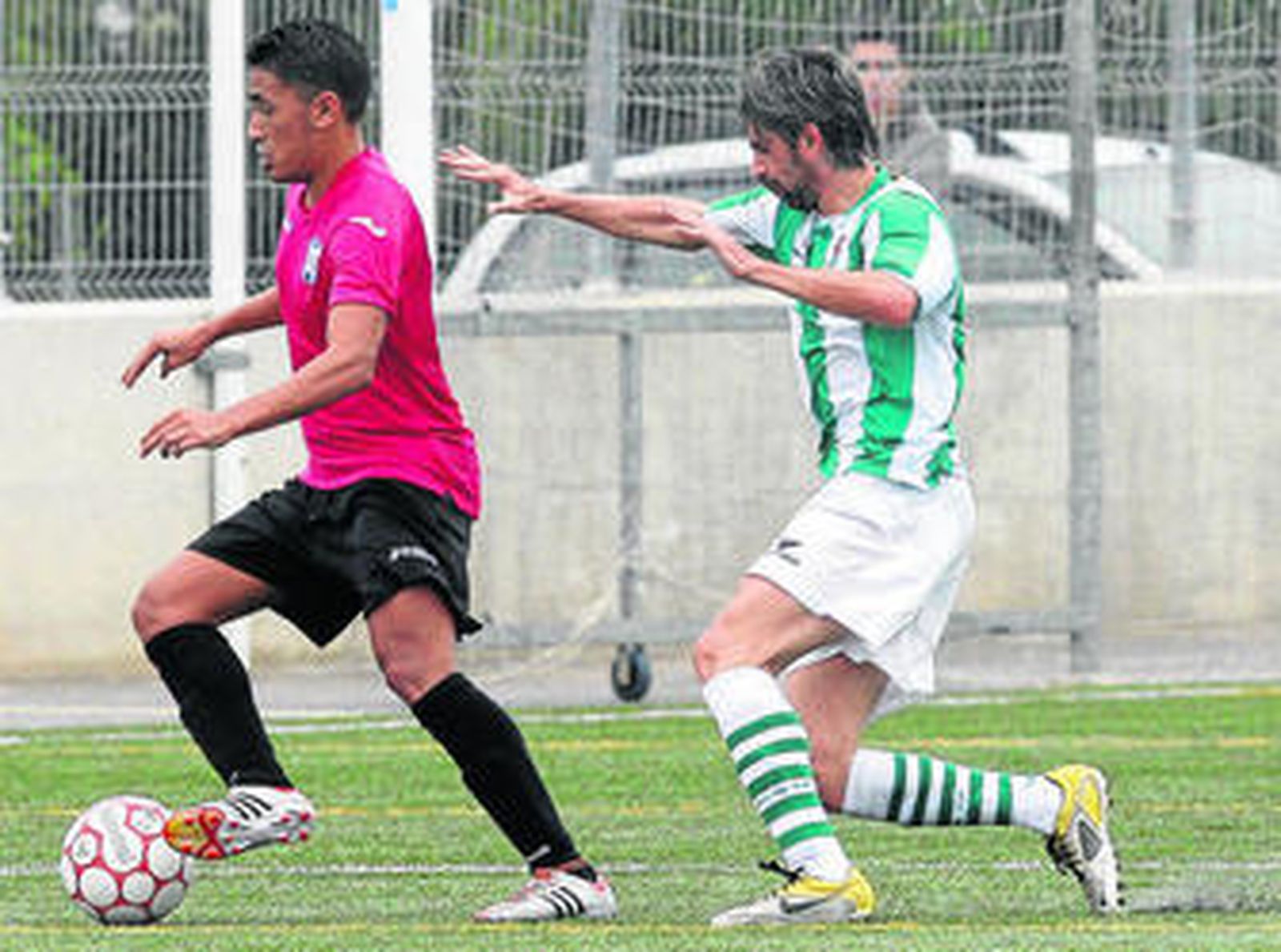 Javi Muñoz (d) presiona a un jugador industrialista que mantiene la posesión del balón.