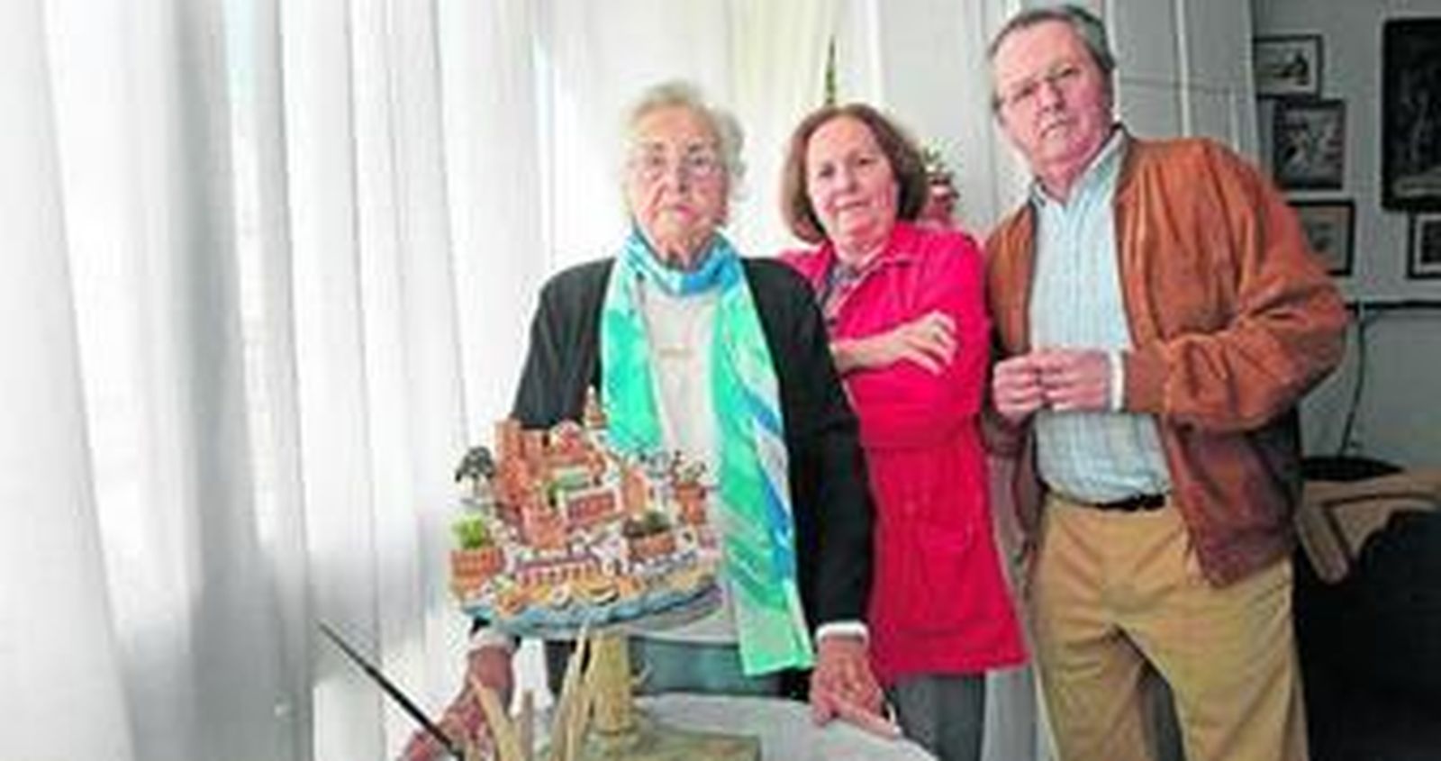 Dolores Santiago mostrando en su casa una de sus obras acompañada por sus hijos María José y Pedro Gómez Santiago.