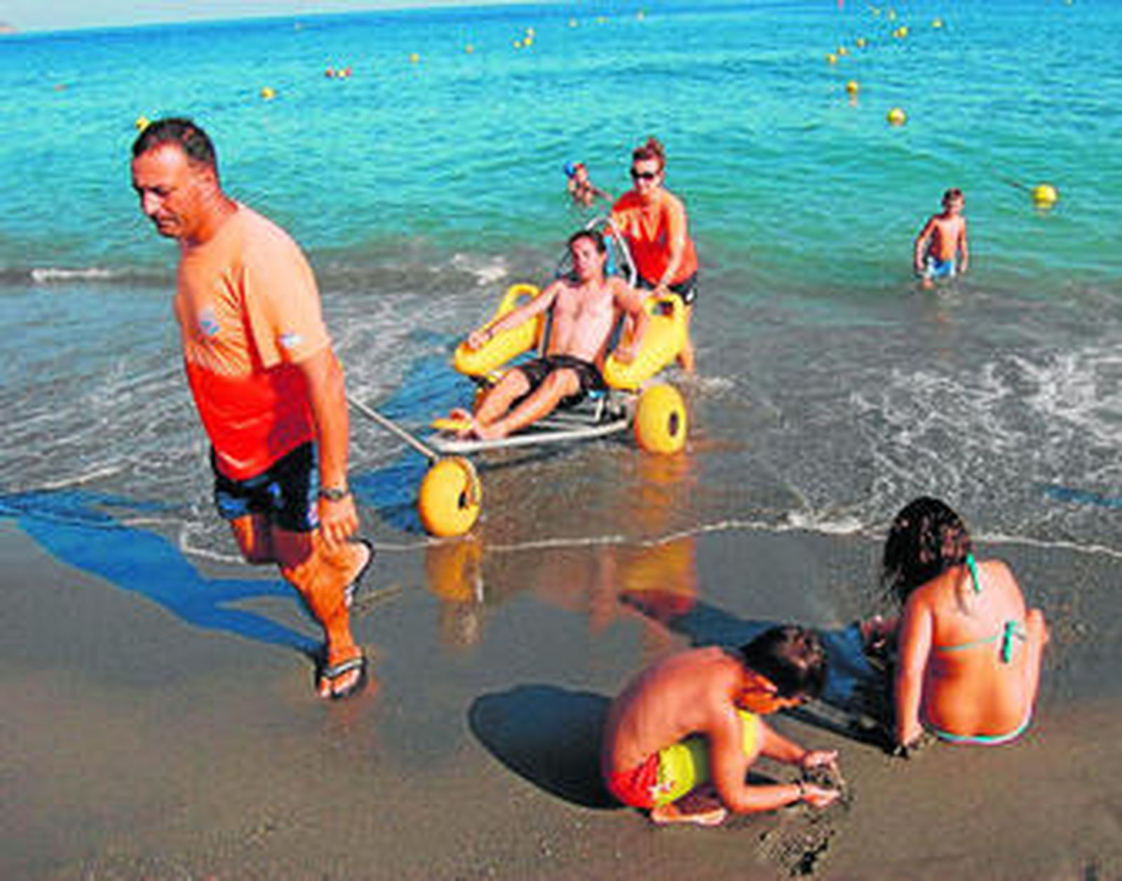Voluntarios de Protección Civil utilizan la silla anfibia para llevar hasta la playa a las personas con alguna discapacidad física.