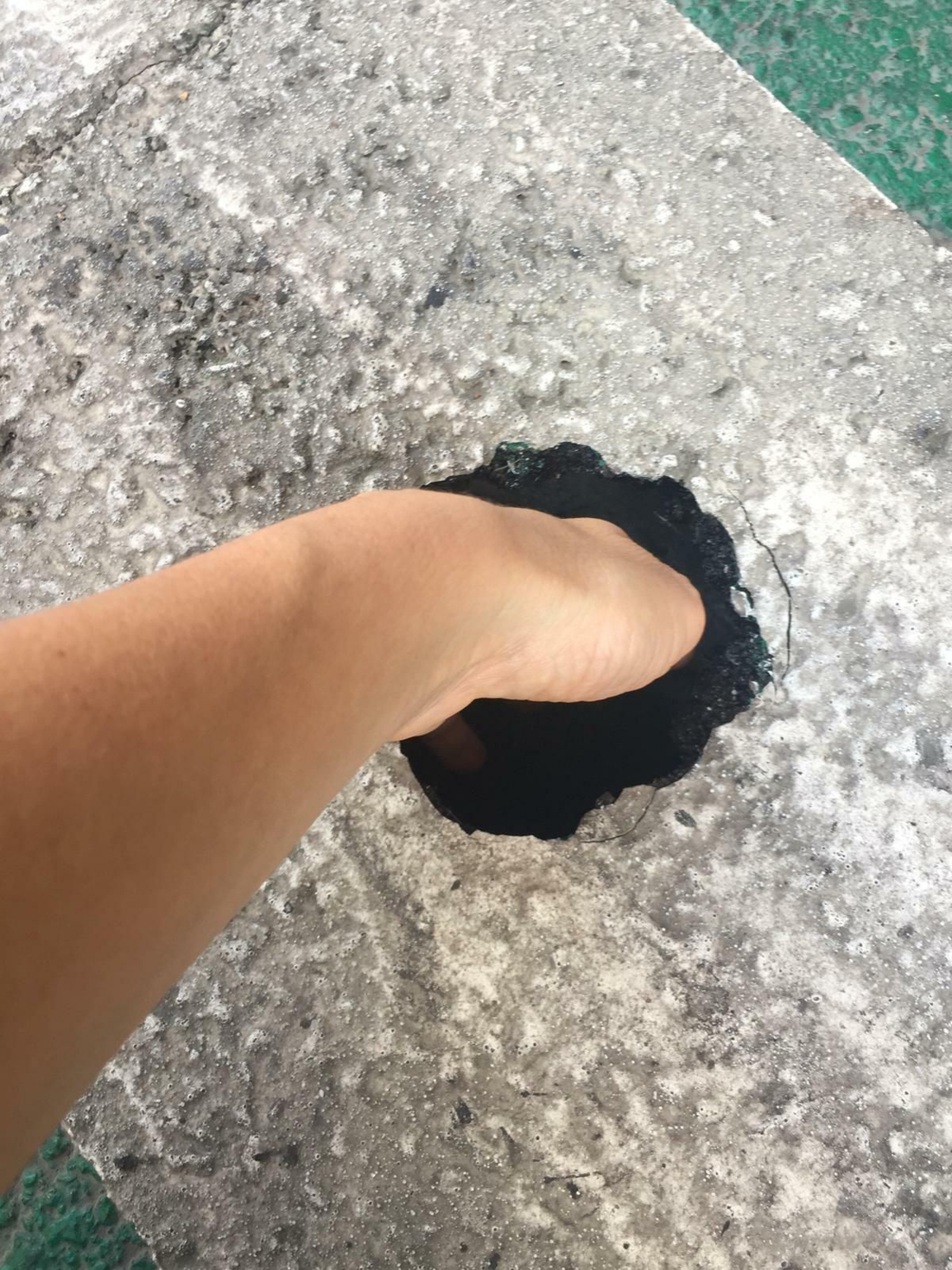 Mano del vecino dentro del agujero que hay en el carril bici de la Avenida de la República Argentina