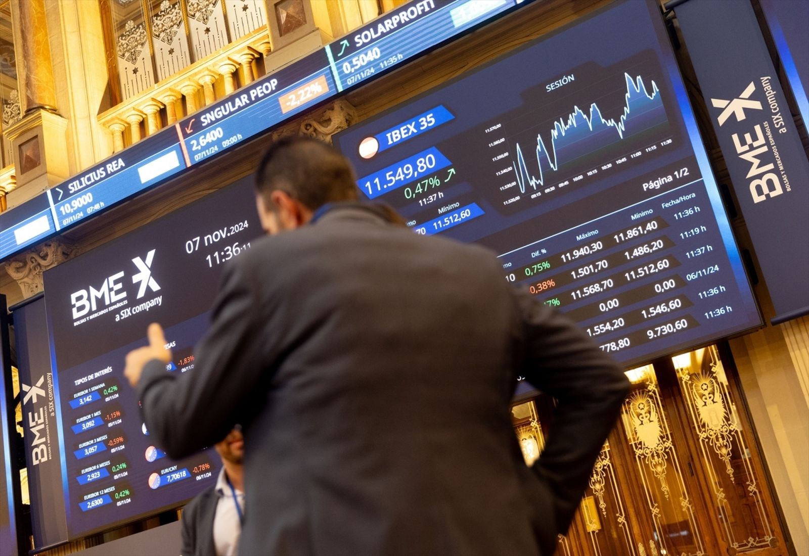 Un hombre pasa por delante de las pantallas con información bursátil en el interior del Palacio de la Bolsa de Madrid.
