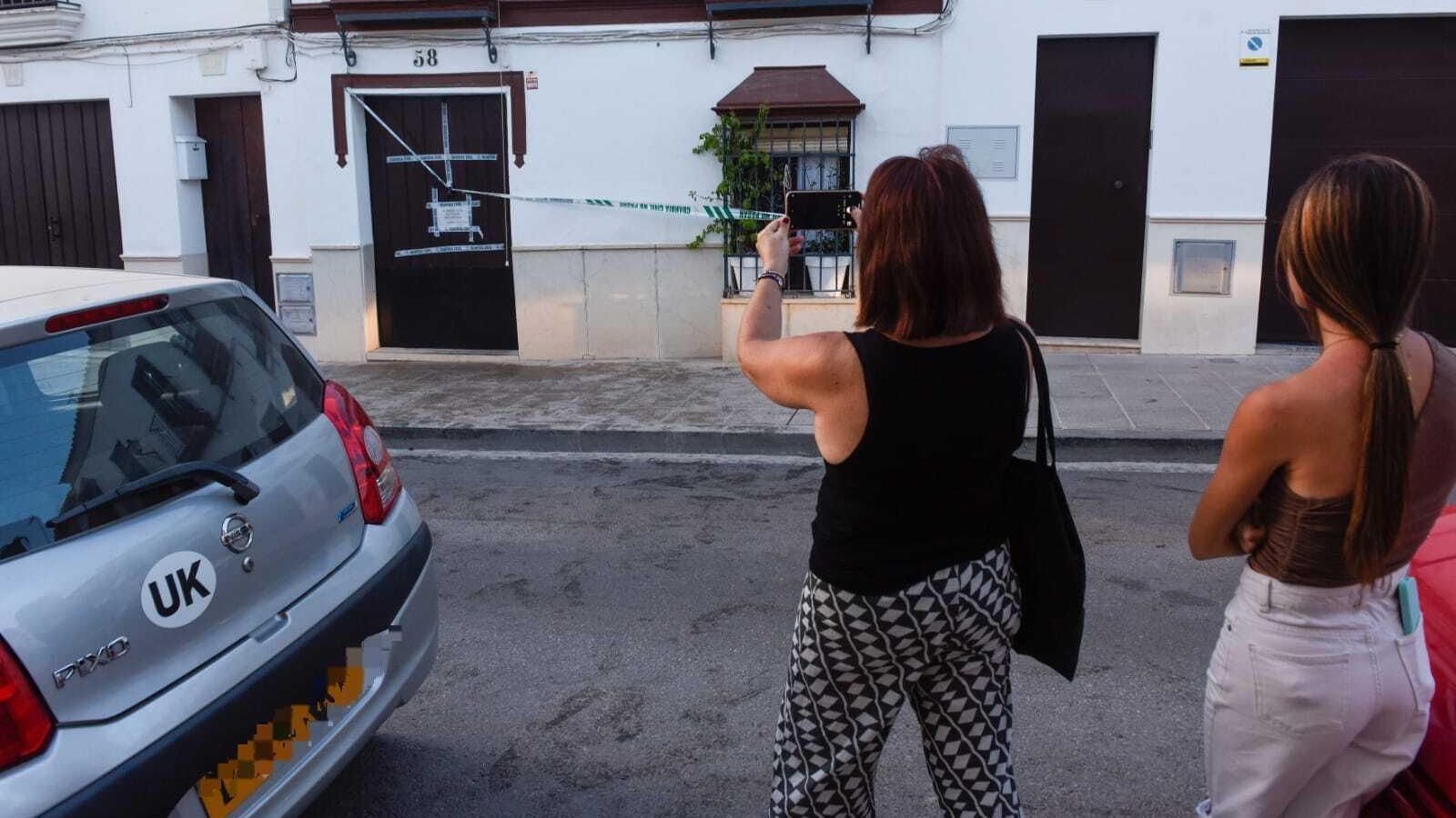 Una periodista hace una fotografía con su móvil de la fachada de la casa, junto al coche de la mujer fallecida.