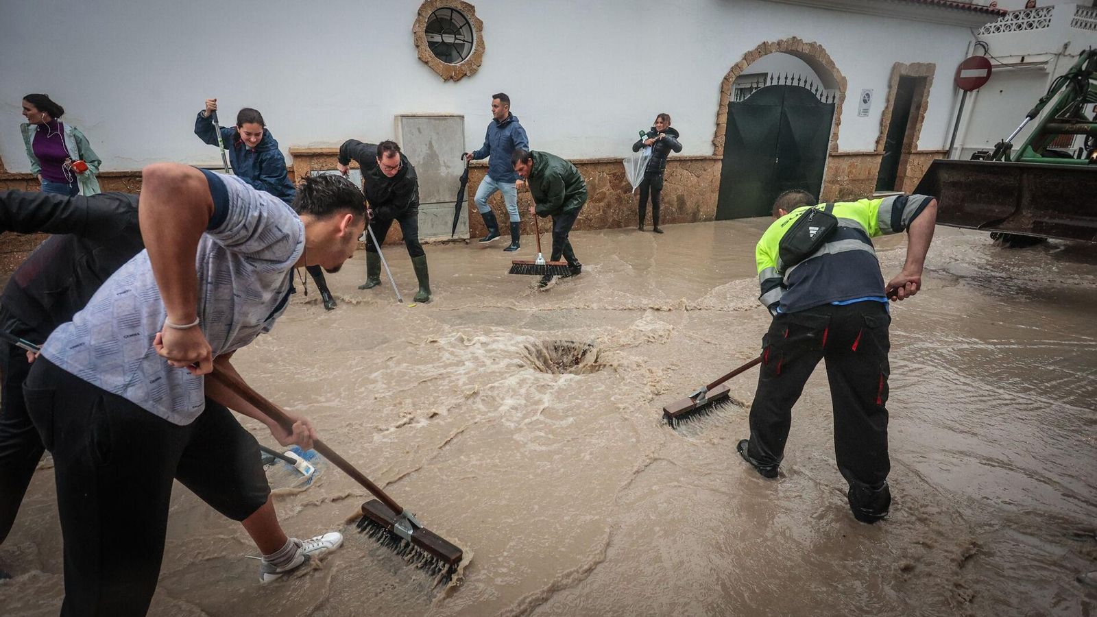 Vecinos de Guadalcacín limpiando una de las calles afectadas por las inundaciones.
