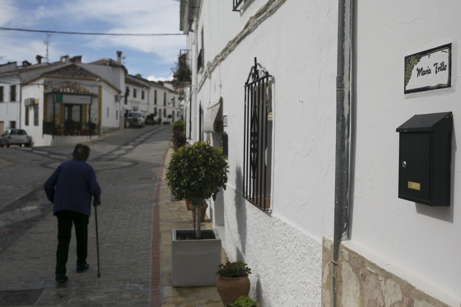 Una mujer pasea por la calle principal de Atajate, en la que se observa una de las placas con nombre de mujer..