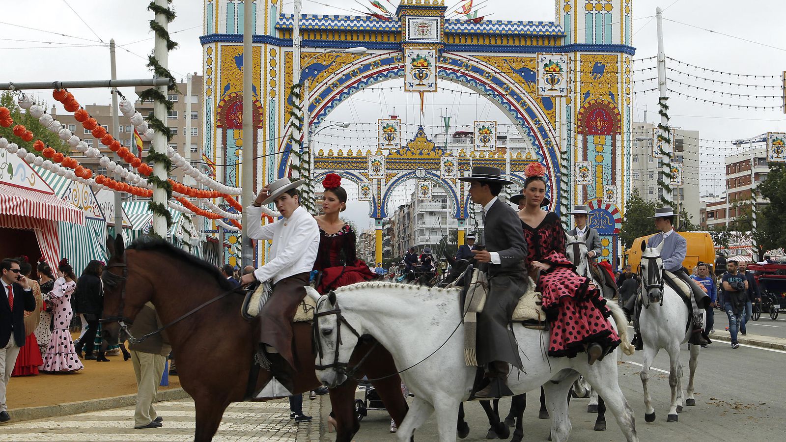 Dos parejas de jinete y amazona por la calle Antonio Bienvenida, con la portada al fondo.