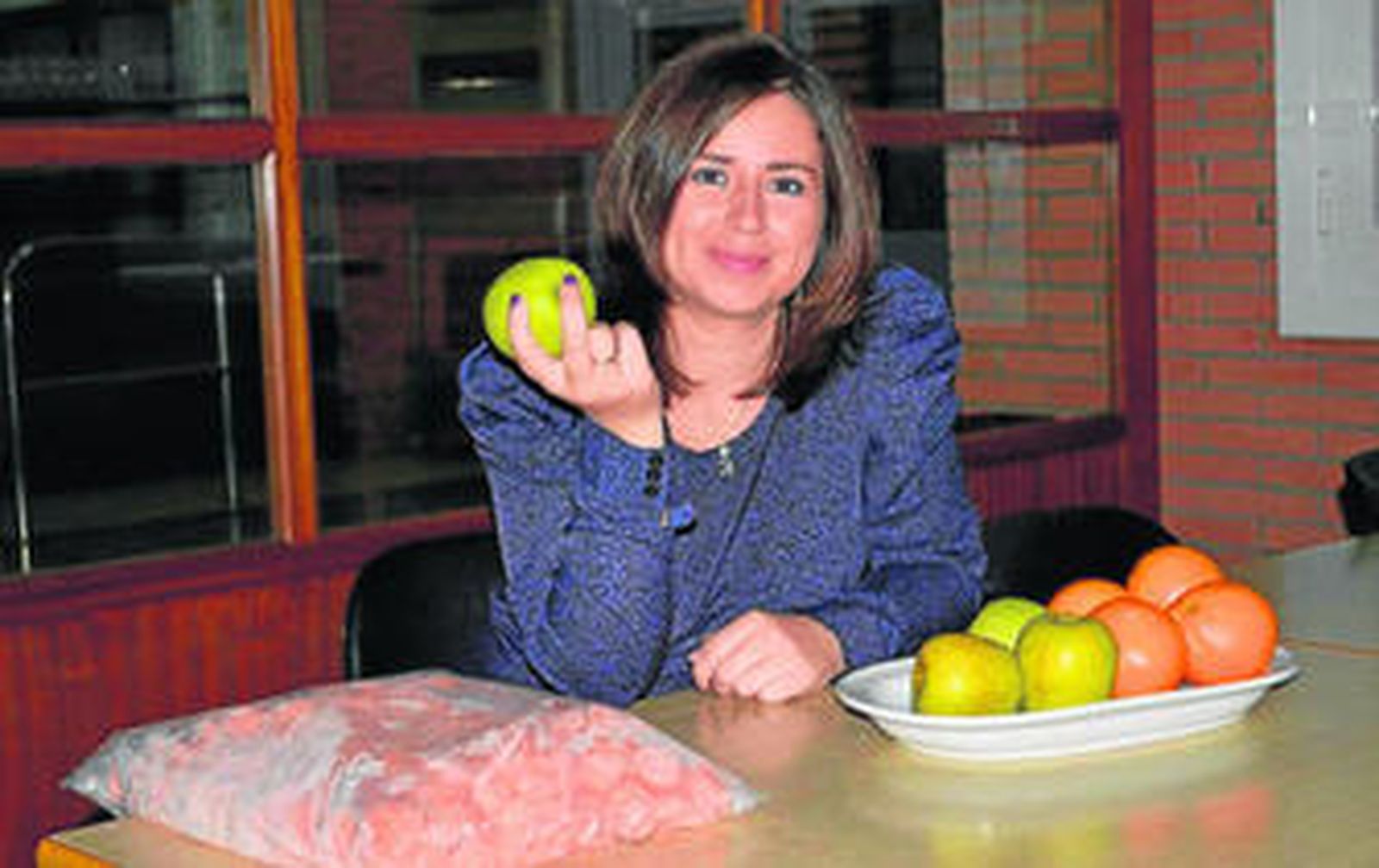 María Isabel Alarcón muestra naranjas y manzanas frescas y una bolsa de zanahoria de IV gama.