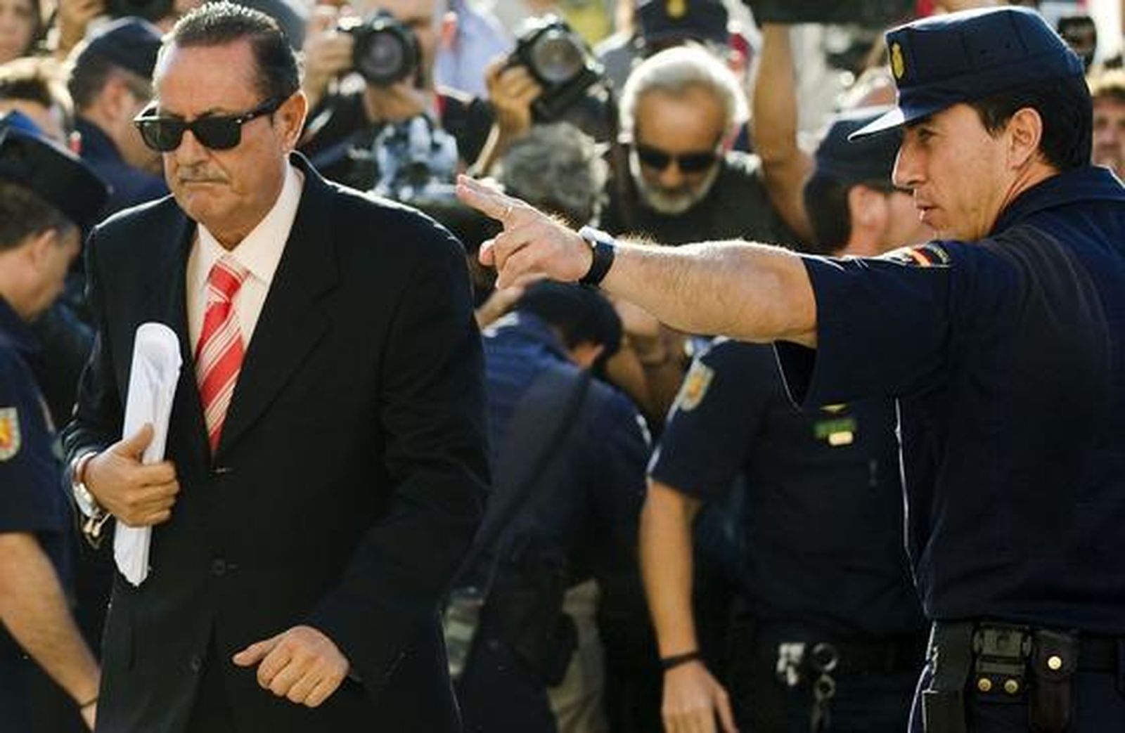 Un olicía nacional indica alel ex alcalde de Marbella Julián Muñoz el camino de entrada a la Audiencia Provincial.