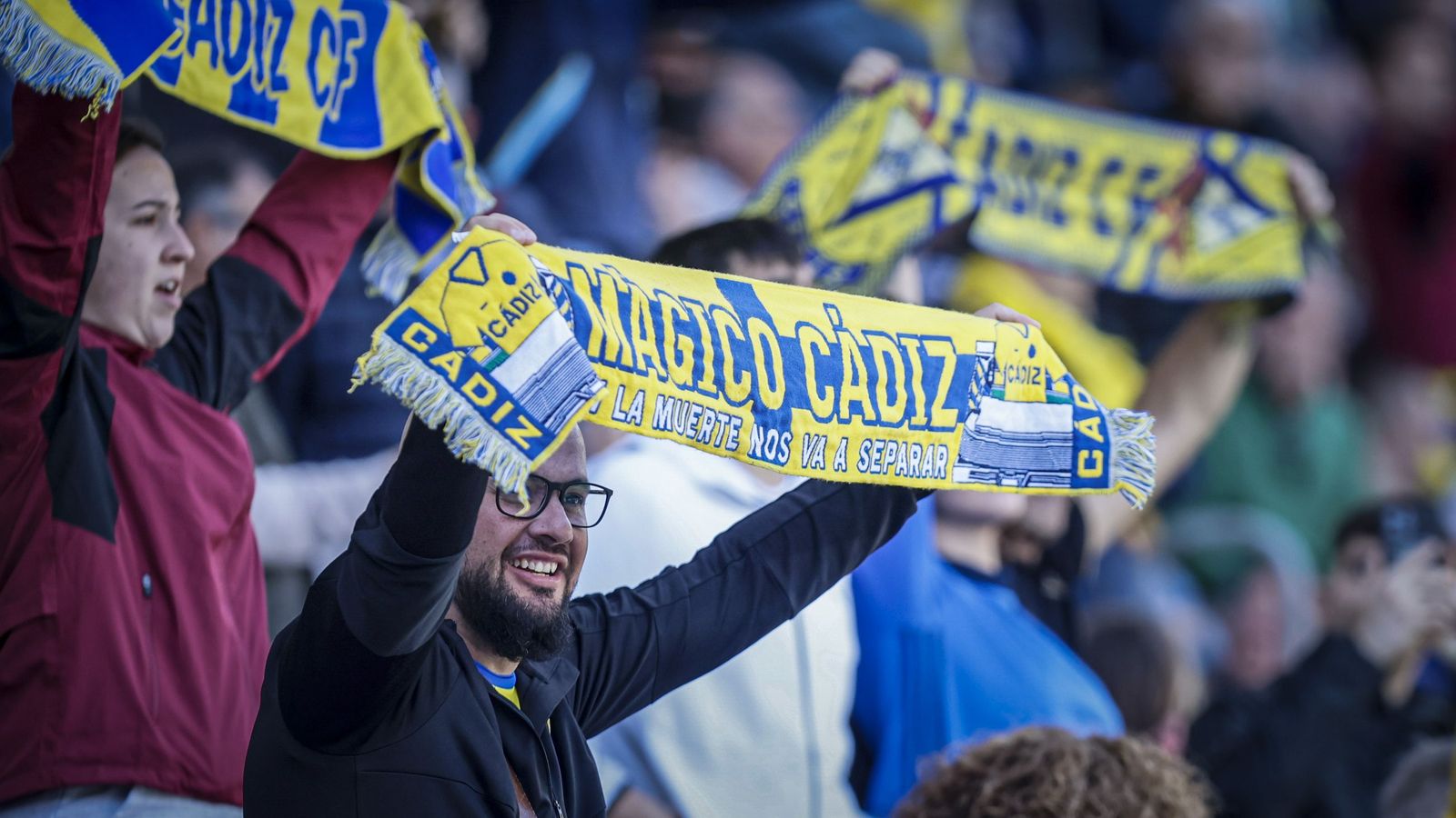 Hinchas del equipo amarillo muestran sus bufandas en un partido.